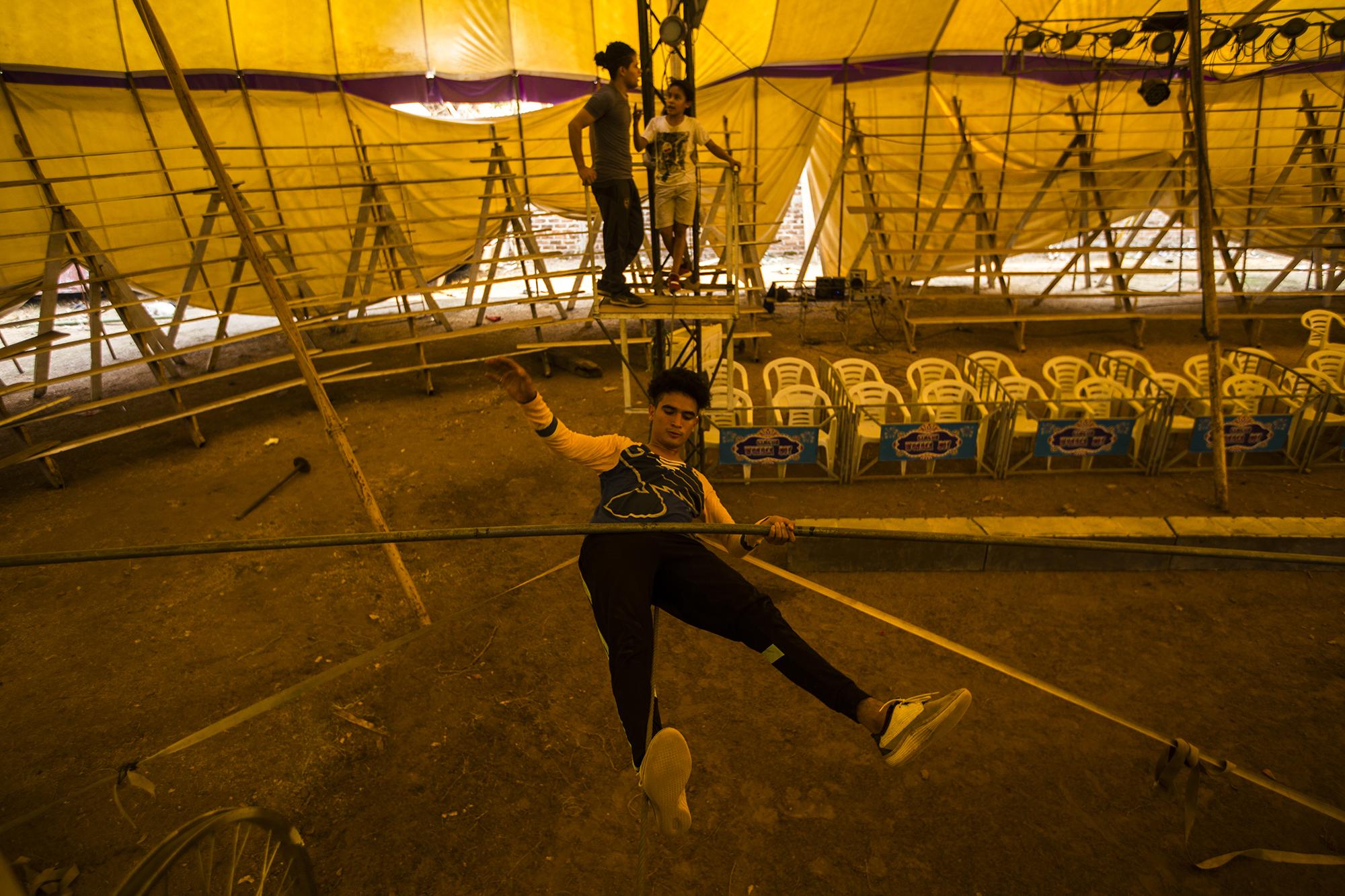 Walter Osorto entrena en la cuerda floja durante la tarde del martes 21 de abril. De 19 años, es acróbata y payaso del circo Wonder Boys, varado en el municipio de Apastepeque, San Vicente. Todos los días realiza la rutina de entrenos junto a sus hermanos. Es parte de su disciplina. Aseguran que deben estar preparados aunque no haya función. Los artistas cumplen la cuarentena en casas rodantes y bajo la carpa. 