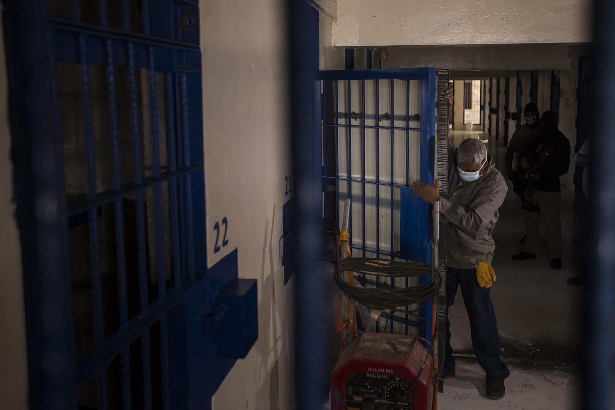 Workers from the Bureau of Prisons place a metalic plate over the bars of cells in Level 2 of the Izalco Prison. The measure was orderd by President Bukele after a rise in murders. The prisoners will not be able to see each other. We