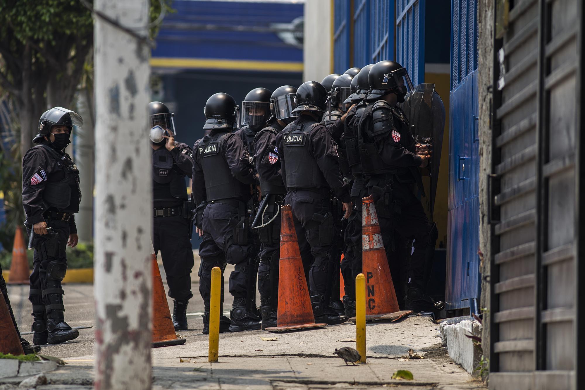 En horas del mediodía, agentes de la Unidad Anti Motines (UMO) rodearon el edificio. La madre de un detenido lloraba muy cerca del cordón policial, mientras se escuchaban los insultos entre policías y un grupo de jóvenes, a través de una transmisión en vivo grabada desde el interior del edificio. Foto de El Faro: Víctor Peña.