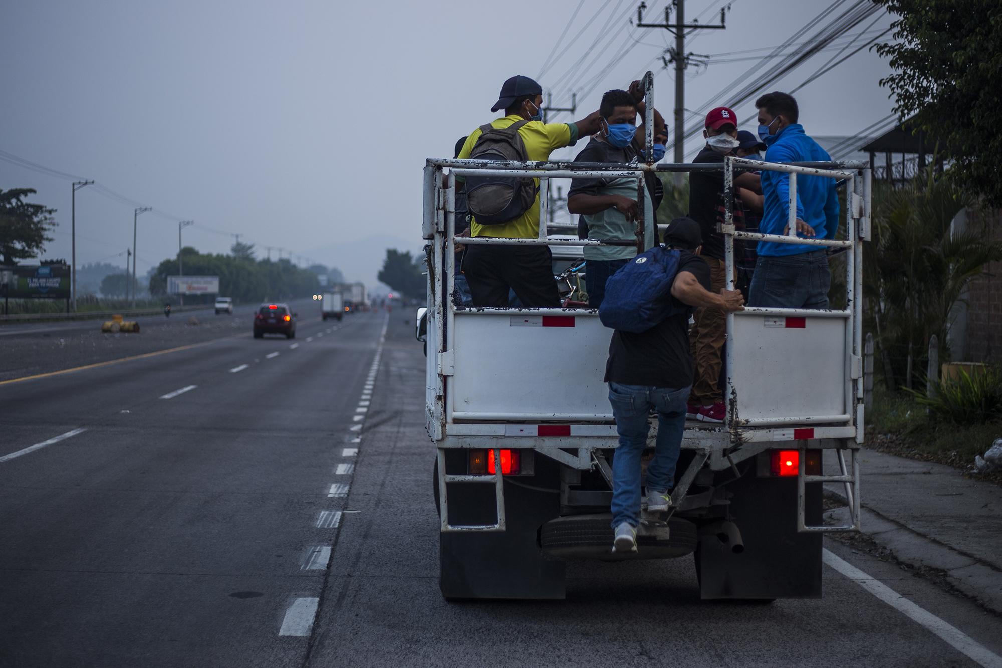 Empledos privados abordan un camión sobre la carretara  que de San Salvador conduce hacia Santa Ana. En horas de la mañana algunos vehículos circulaban para recoger a sus empleados. En las paradas de autobuses, muhos no lograban encontrar transporte. Foto de El Faro: Víctor Peña.