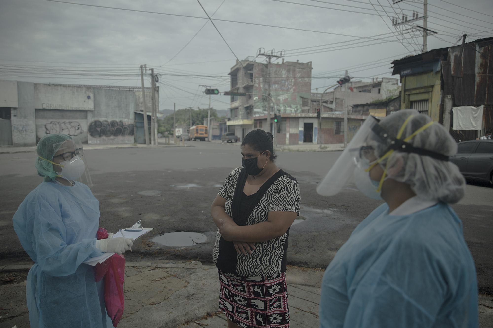 Dos trabajadoras del Ministerio de Salud entrevistan a María del Carmen Montoya, pareja de un hombre que fue trasladado a un centro asistencial por problemas respiratorios y que desde hace cuatro días no regresa al mesón. Foto de El Faro: Carlos Barrera