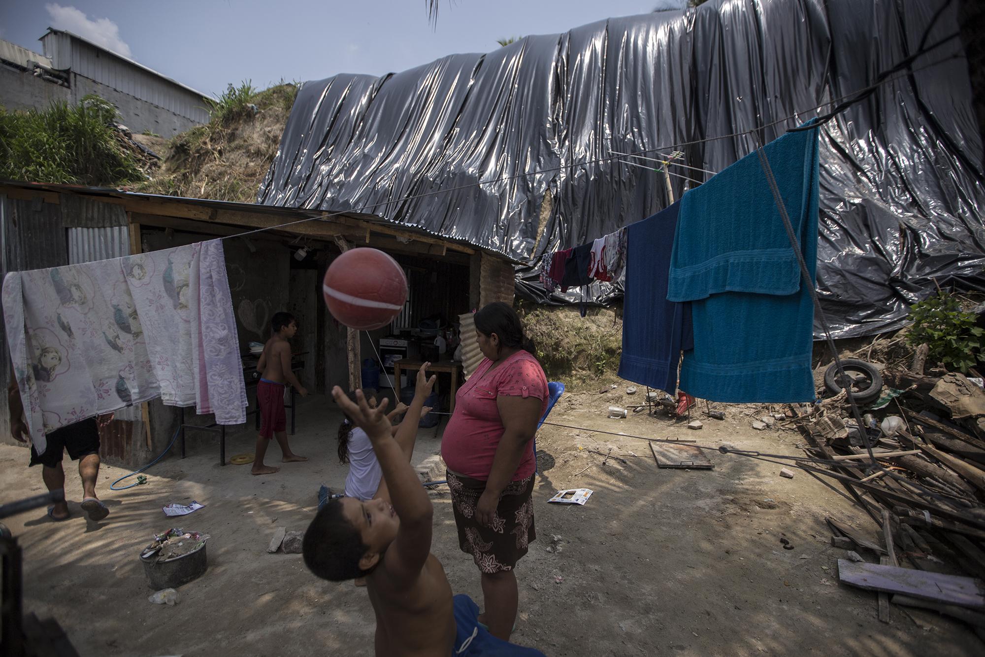 Fátima y su familia viven bajo amenaza. Cada vez que llueve, trozos de tierra golpean su hogar. Es la última casa del pasaje A, de la comunidad 15 de Marzo, donde los plásticos que la comunidad ha colocado previenen más deslave. Fátima y su esposo son los dueños de “Tacos El Chero”, un negocio ambulante en las plazas del Centro Histórico de San Salvador, y que desde el sábado 14 de marzo no ha tenido ingresos. Foto de El Faro: Víctor Peña.