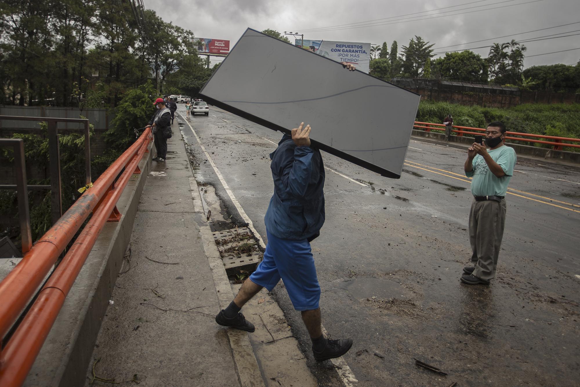 Desde las primeras horas del domingo 31 de mayo, y en medio de la lluvia, los habitantes de la comunidad Nuevo Israel, se esforzaban por rescatar las pocas pertenencias que les dejó la lluvia. En la imagen, un hombre carga un televisor plasma que sobrevivió a Amanda. 