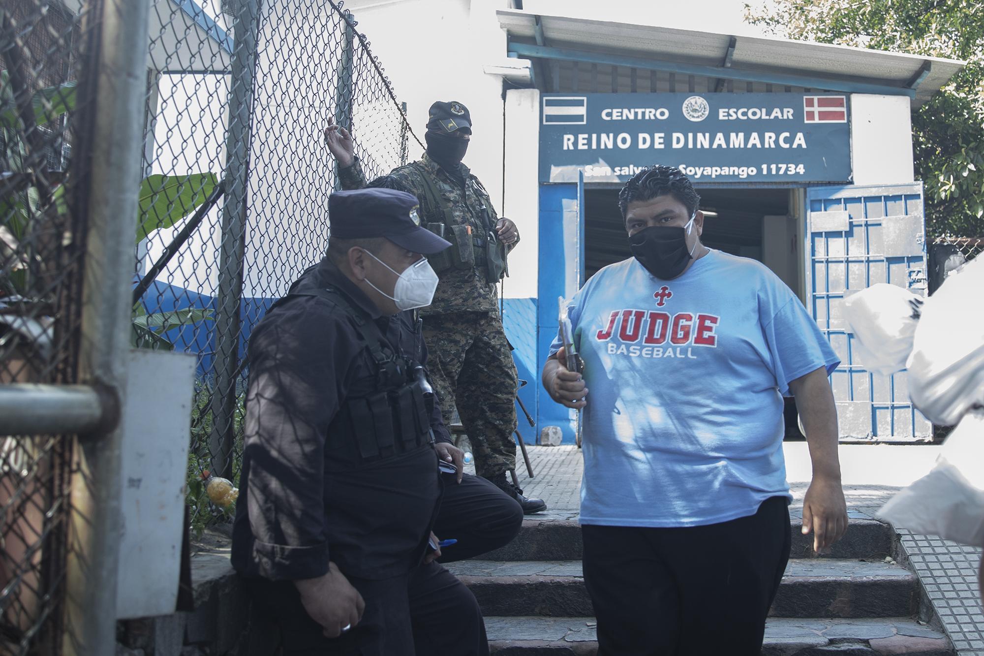 Carlos Mauricio Canizales secretario municipal de Nuevas Ideas pide a un agente policial que impida el ingreso de periodistas de El Faro al centro escolar donde  funcionaba el centro de distribución de alimentos en Soyapango, el 12 de junio de 2020. Foto de El Faro: Carlos Barrera