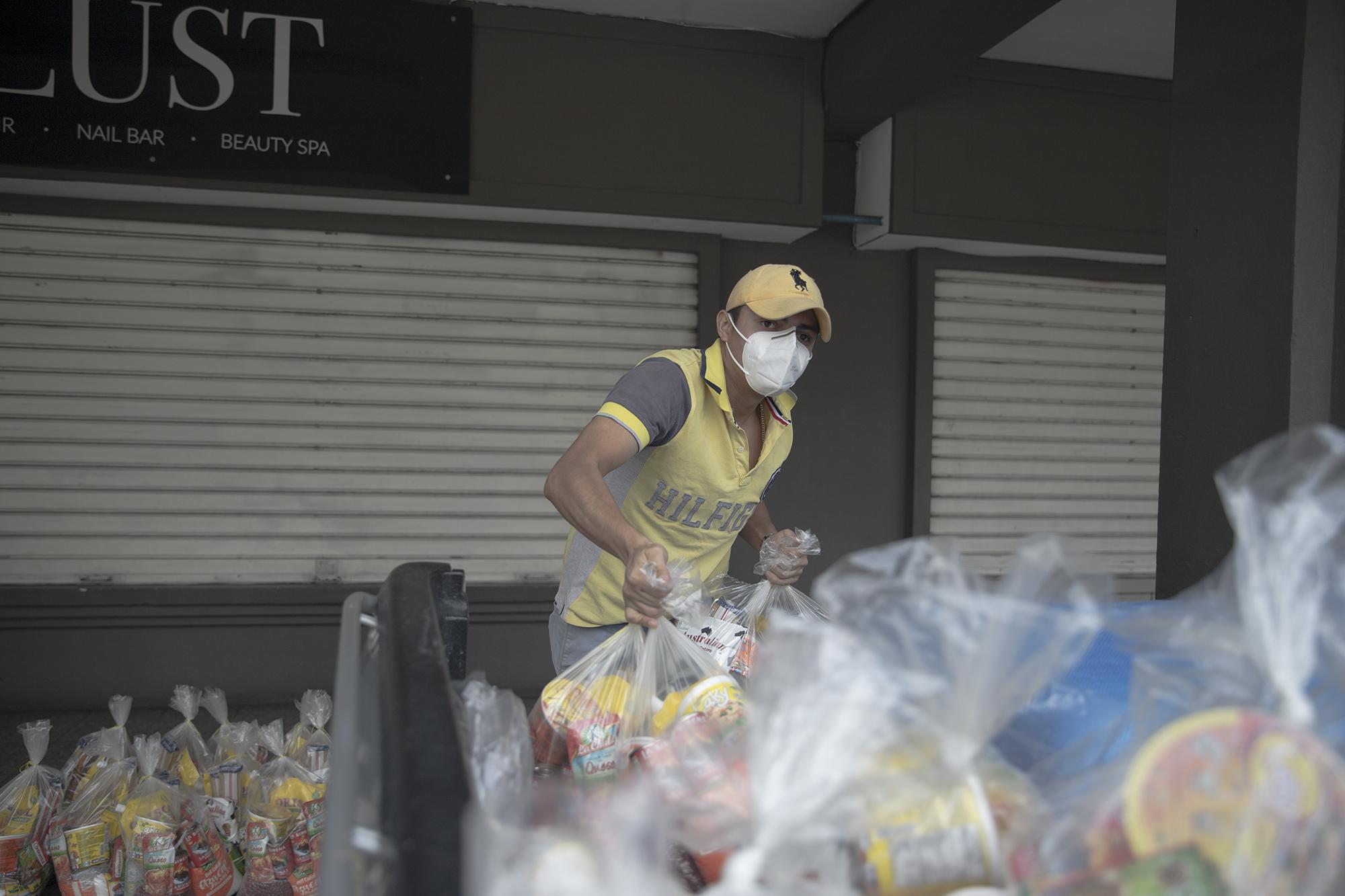 Levy Ponce, de 20 años, carga bolsas con víveres para ser repartidos en el oriente de El Salvador a las familias que han sido afectadas por la crisis económica causada por el coronavirus. Foto de El Faro: Carlos Barrera.