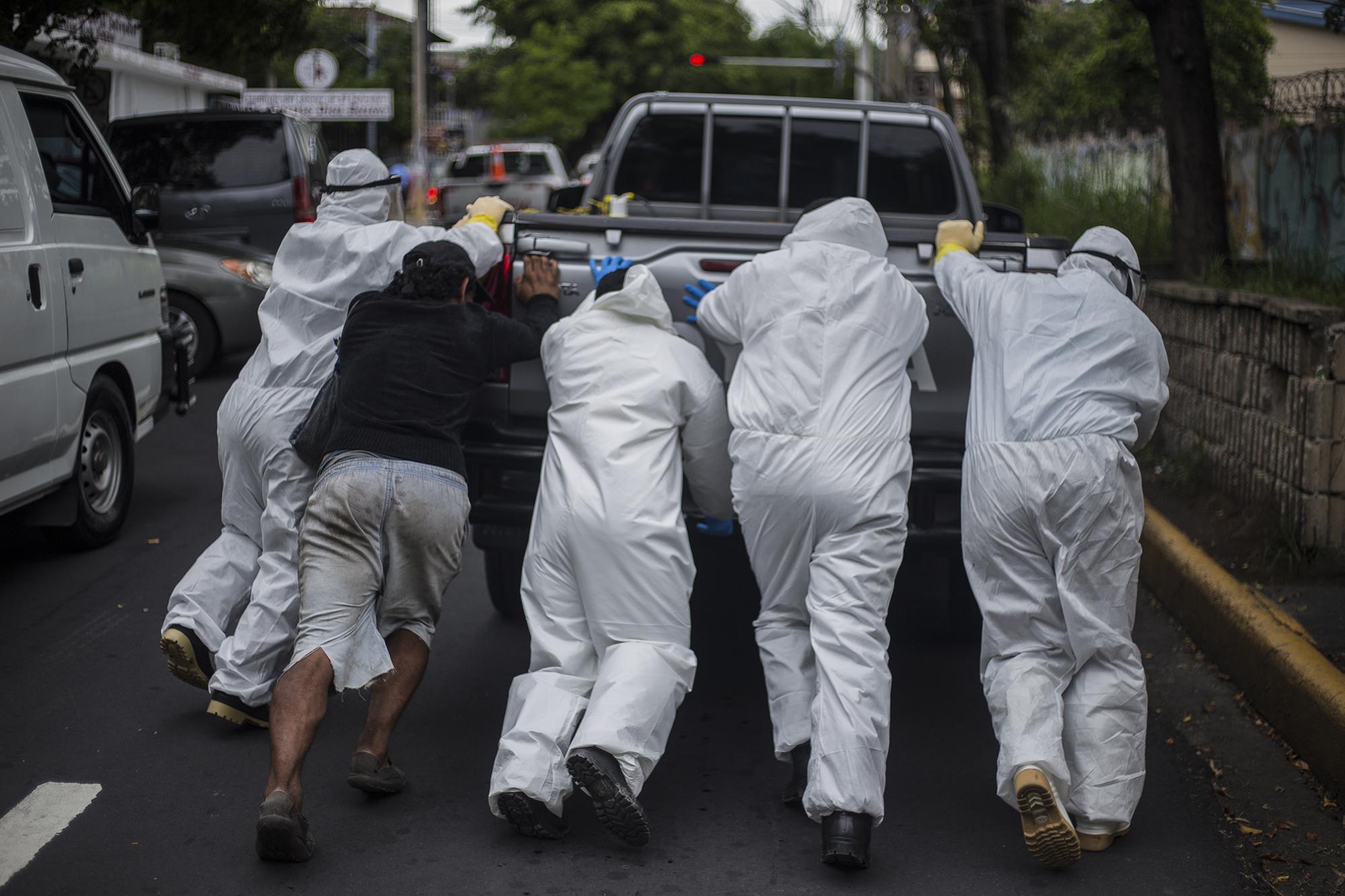 From 9 am to 3:30 pm every day, cars from funeral homes line up outside the Rosales Hospital in San Salvador to collect the bodies of confirmed or suspected victims of covid-19. “Once we found 35 victims at the morgue. We sent out 18. The next day I arrived at 6 in the morning and we found another 35 bodies,” recounts a police officer standing guard outside the hospital. Above, a group of funeral workers tries to jump start a car that caused a bottleneck outside the entrance of the morgue.