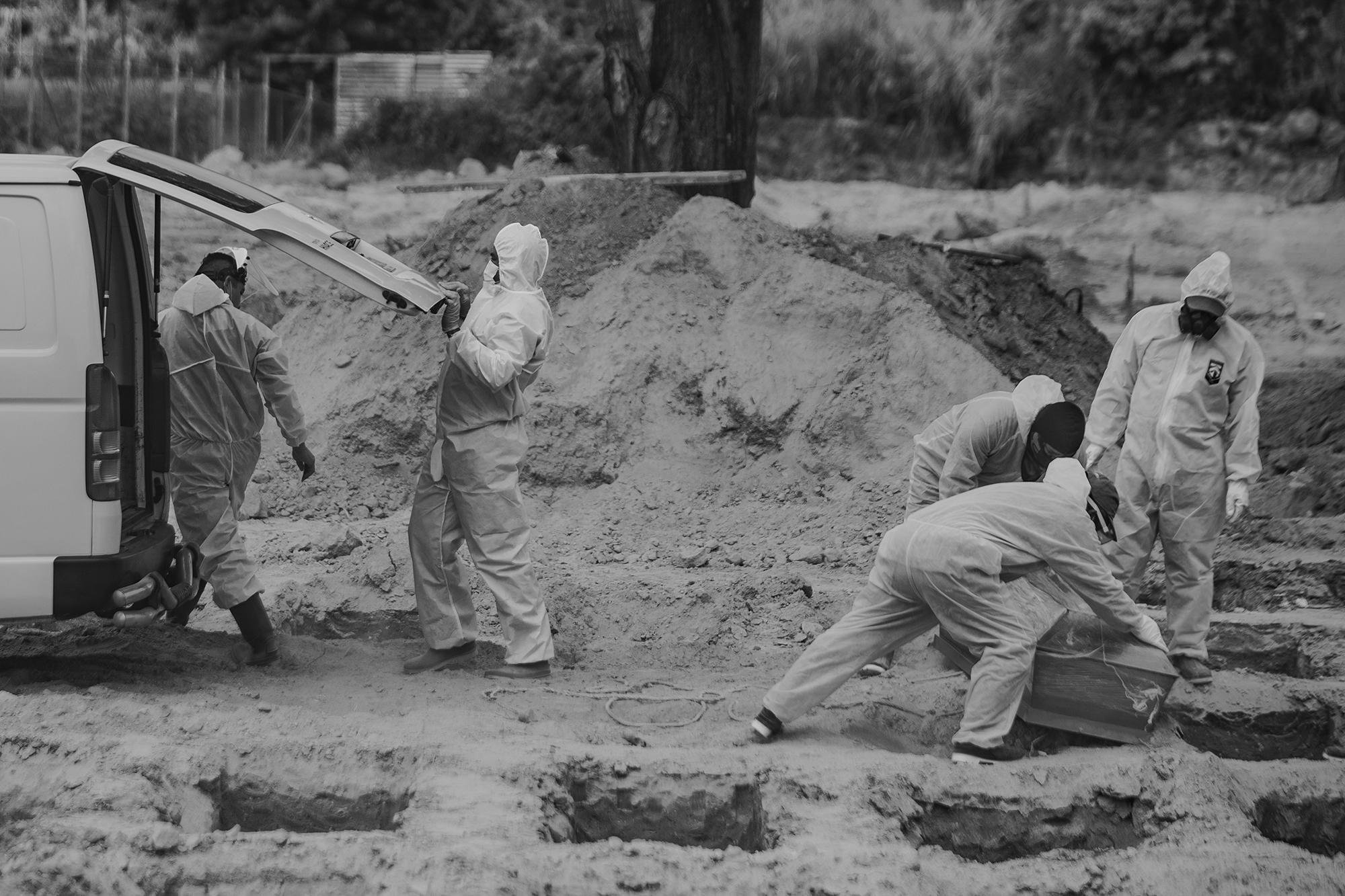 Santos cierra la compuerta de la carroza fúnebre después de entregar el ataúd a los enterradores del cementerio La Bermeja. Al interior de la caja de madera va el cuerpo de una persona que murió con síntomas similares a los de la covid-19 en el hospital Amatepec del Seguro Social, en Soyapango.