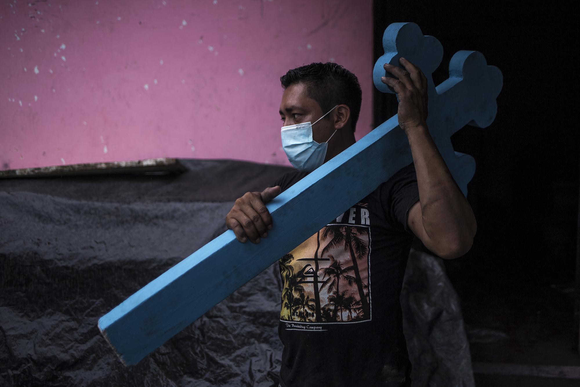 Cuando los compañeros de Pedro se enteraron de la muerte de su sobrina, entre todos reunieron $53 para ayudar con los gastos del funeral. Asignaron un ataúd blanco que se fabricó en el mismo taller, pintaron una cruz de cemento y colocaron el nombre de la fallecida. En la imagen, Omar Pérez, de 29 años, camina hacia el cementerio general del municipio de San Pedro Perulapán. Omar, en su tiempo libre, ayuda al propietario con la entrega de ataúdes.