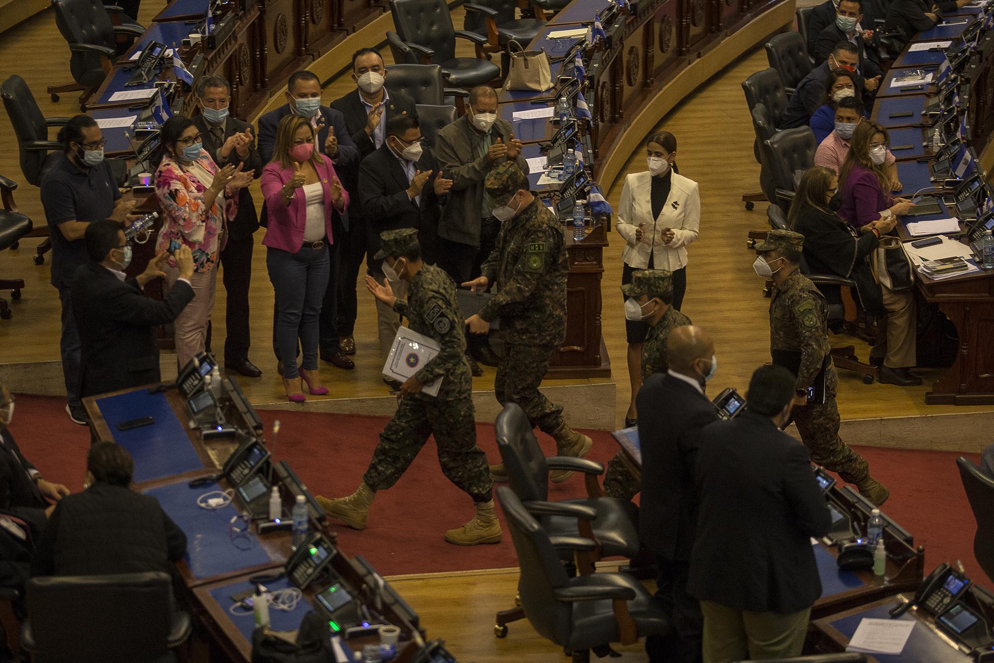 Doce horas depués, el ministro de Defensa se retira del Salón Azul de la Asamblea Legislativa, donde fue interpelado por los diputados, sobre los hechos ocurridos el 9 de febrero, cuando la Fuerza Aramada se tomó las instalaciones de la Asamblea Legislativa. Los diputados afines al Gobierno aplauden su salida. Foto de El Faro: Víctor Peña.