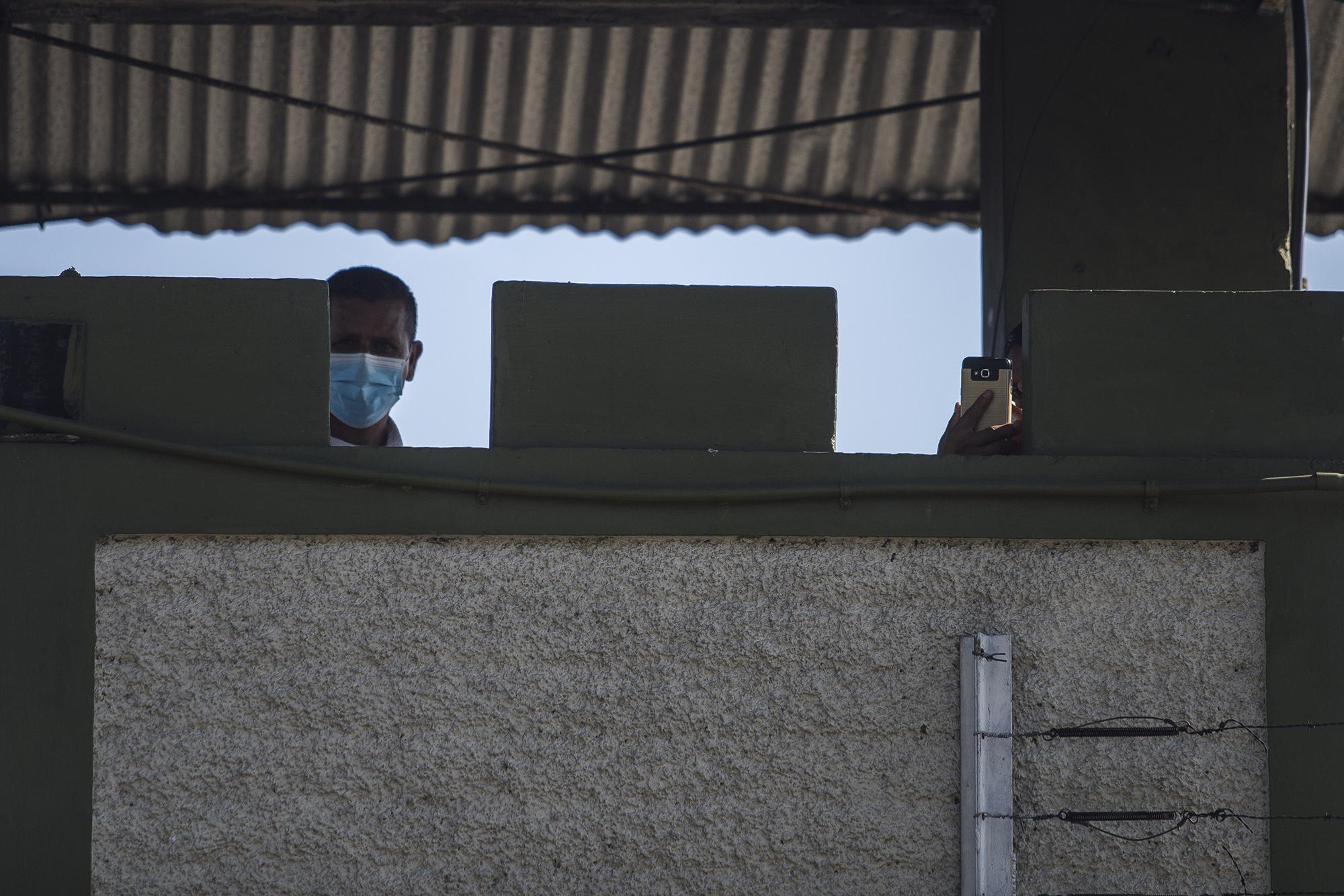 Desde una garita de vigilancia, dos militares tomaban fotografías y amedrentaban a periodistas, mientras el juez, Fiscalía y querellantes intentaban acceder a las instalaciones del Estado Mayor. Foto de El Faro: Víctor Peña. 