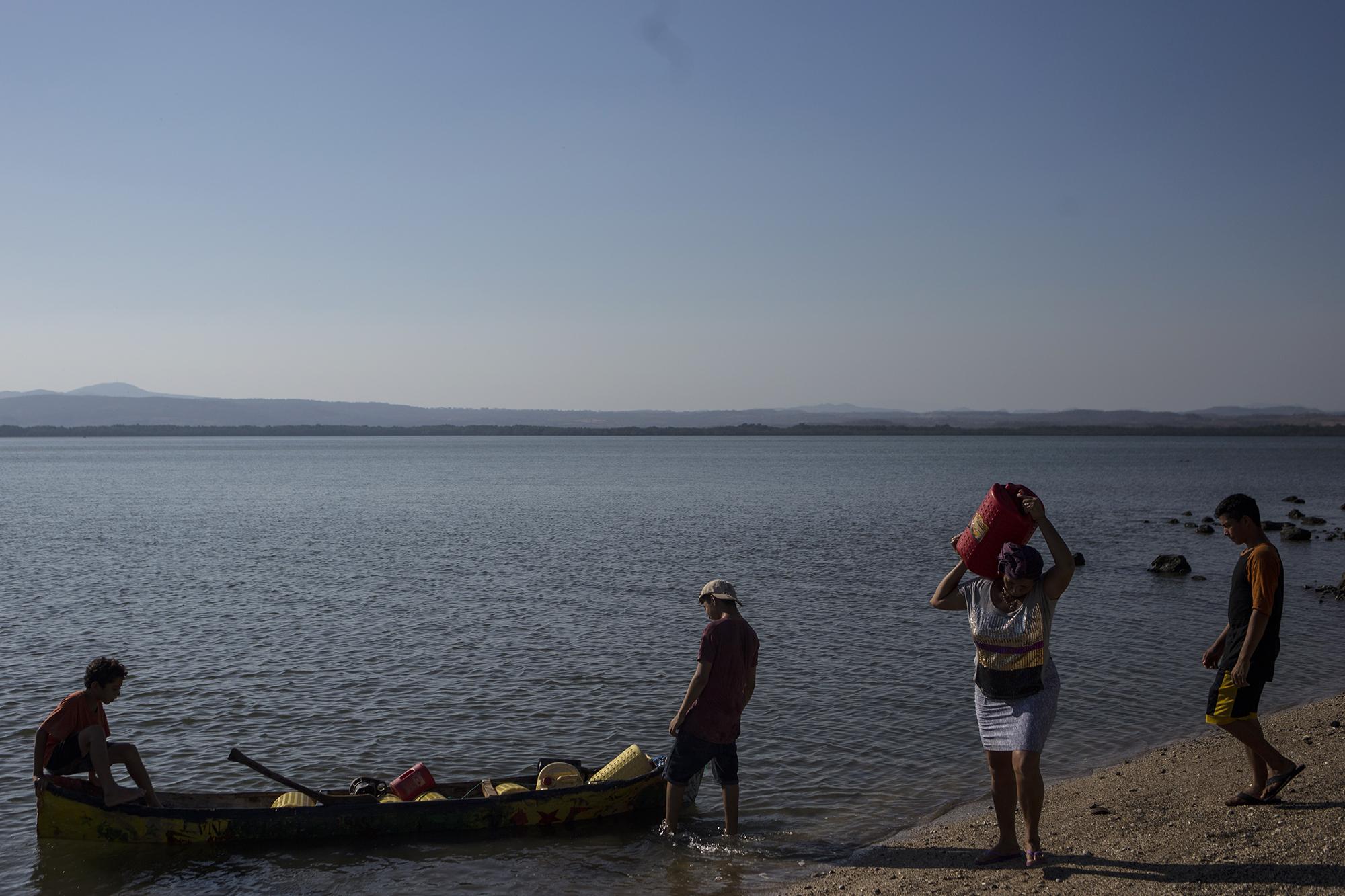 Cándida carga un recipiente con agua. Cada día suben los recipientes plásticos a una lancha, recorren el trayecto de un kilómetro y extraen líquido en las cercanías de la isla Perico. Exploran algunos pozos de agua semidulce  que la comunidad ha abierto, y que sirve para la cocina, para bañarse, para lavar la ropa y para los oficios de la cocina. Cuando viajan a La Unión, Cándida y Santiago hacen un trueque con los habitantes de esa ciudad. Intercambian sus pescados por agua para beber. “Aquí el agua se cuida como cuidar sus ojos”, dice Cándida.