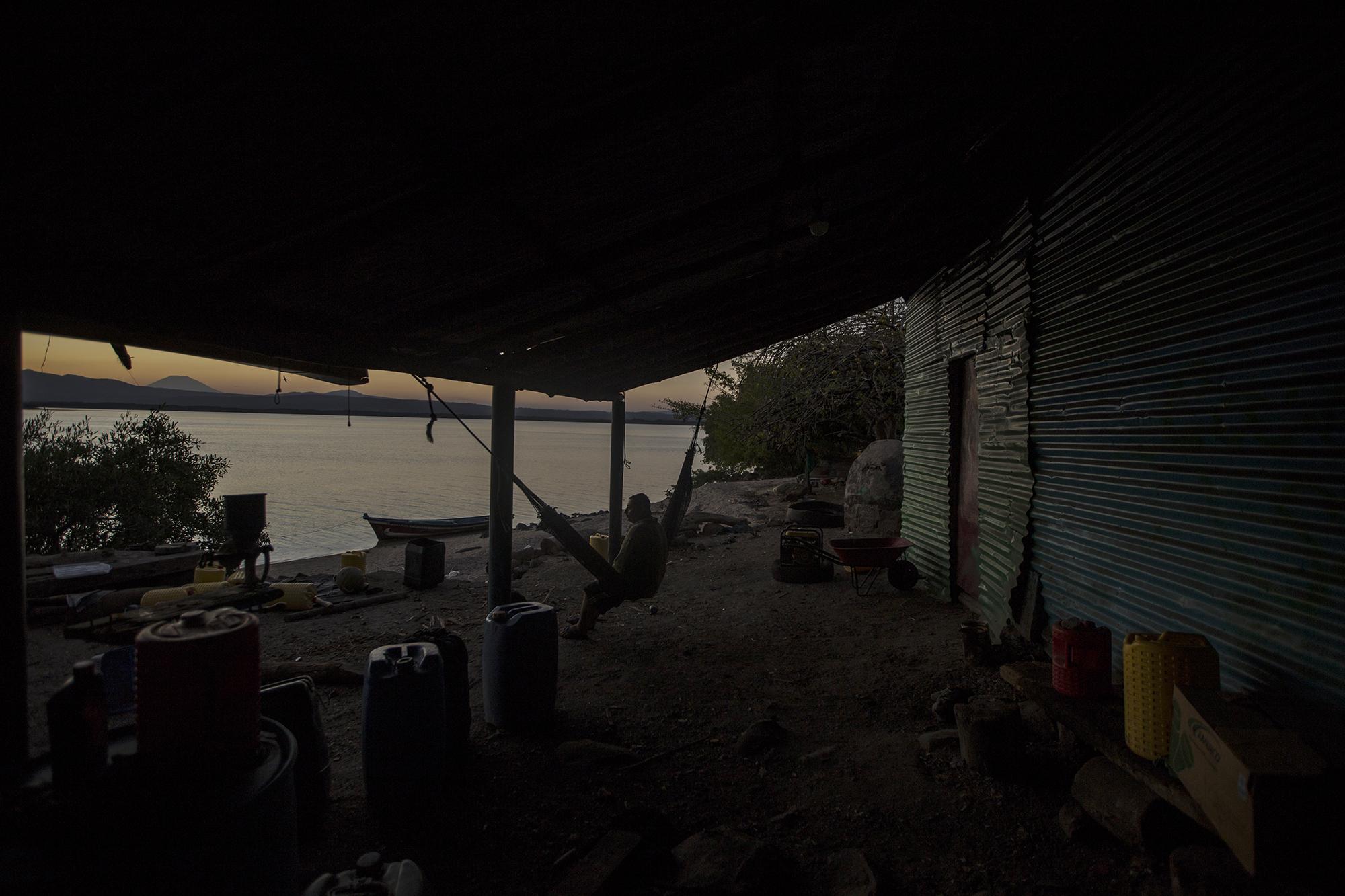 Santiago contempla el atardecer desde Periquito. Él es propietario de una vivienda en La Unión, pero prefirió abandonarla para vivir en un espacio alejado de la violencia de la ciudad. Santiago decidió aislarse. Su aislamiento también lo hizo rechazar la petición de dejarse hacer un retrato para esta fotogalería.  Argumentó que, hasta para tomarse la fotografía de su Documento Único de Identidad, alguien tuvo que persuadirlo. Santiago no sabe leer ni escribir una sola palabra, más que sus iniciales para firmar algún documento cuando es necesario. 