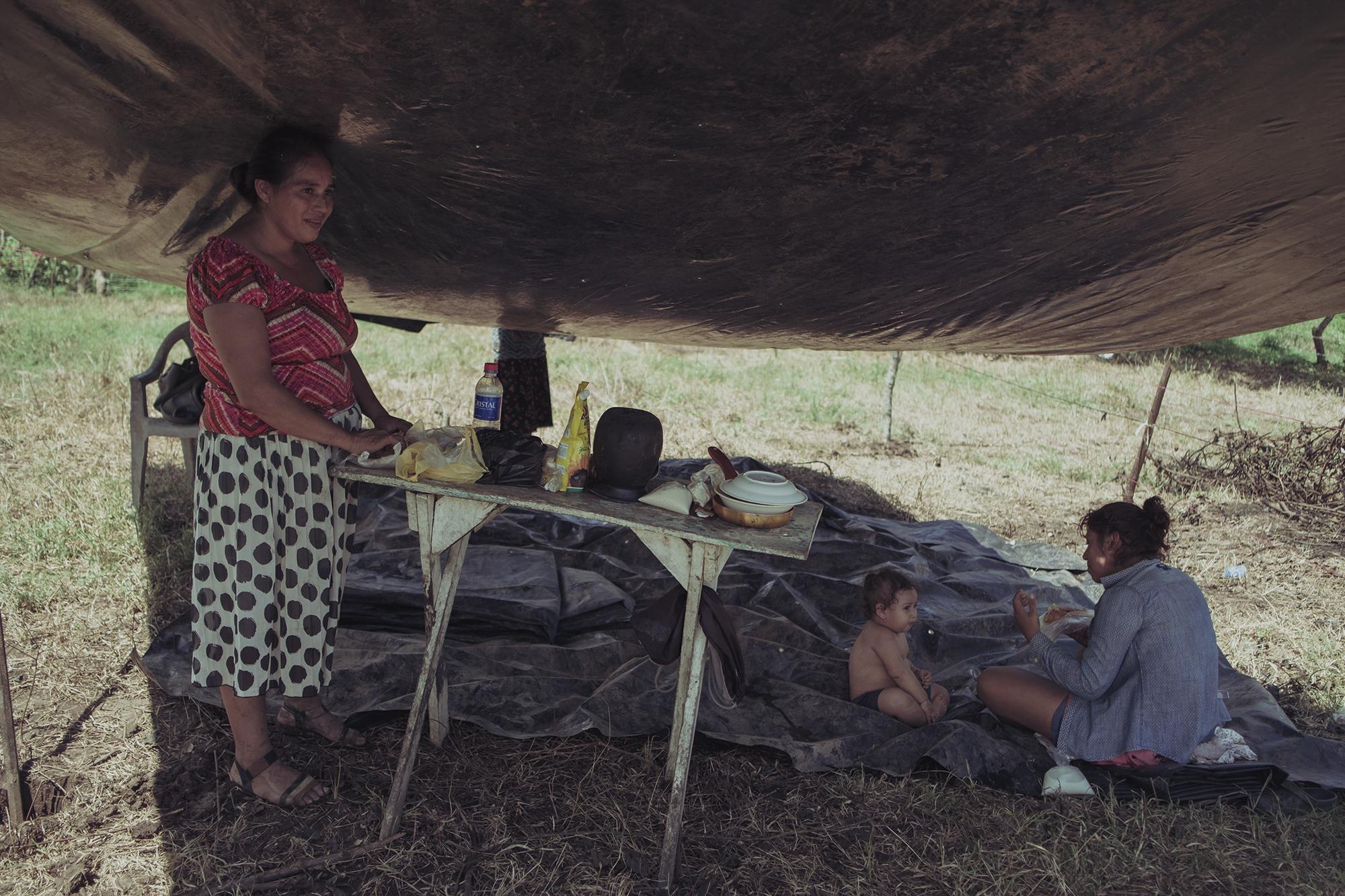 Hora del almuerzo en la carpa de Delmy Chicas, de 30 años. Al igual que otros, ella ha buscado un espacio porque ya no pudo pagar la renta en su antiguo hogar. Con su pareja tienen tres hijos. Él se dedica a lavar buses en la ciudad de San Miguel. El transporte público estuvo cerrado durante meses debido a la cuarentena. 