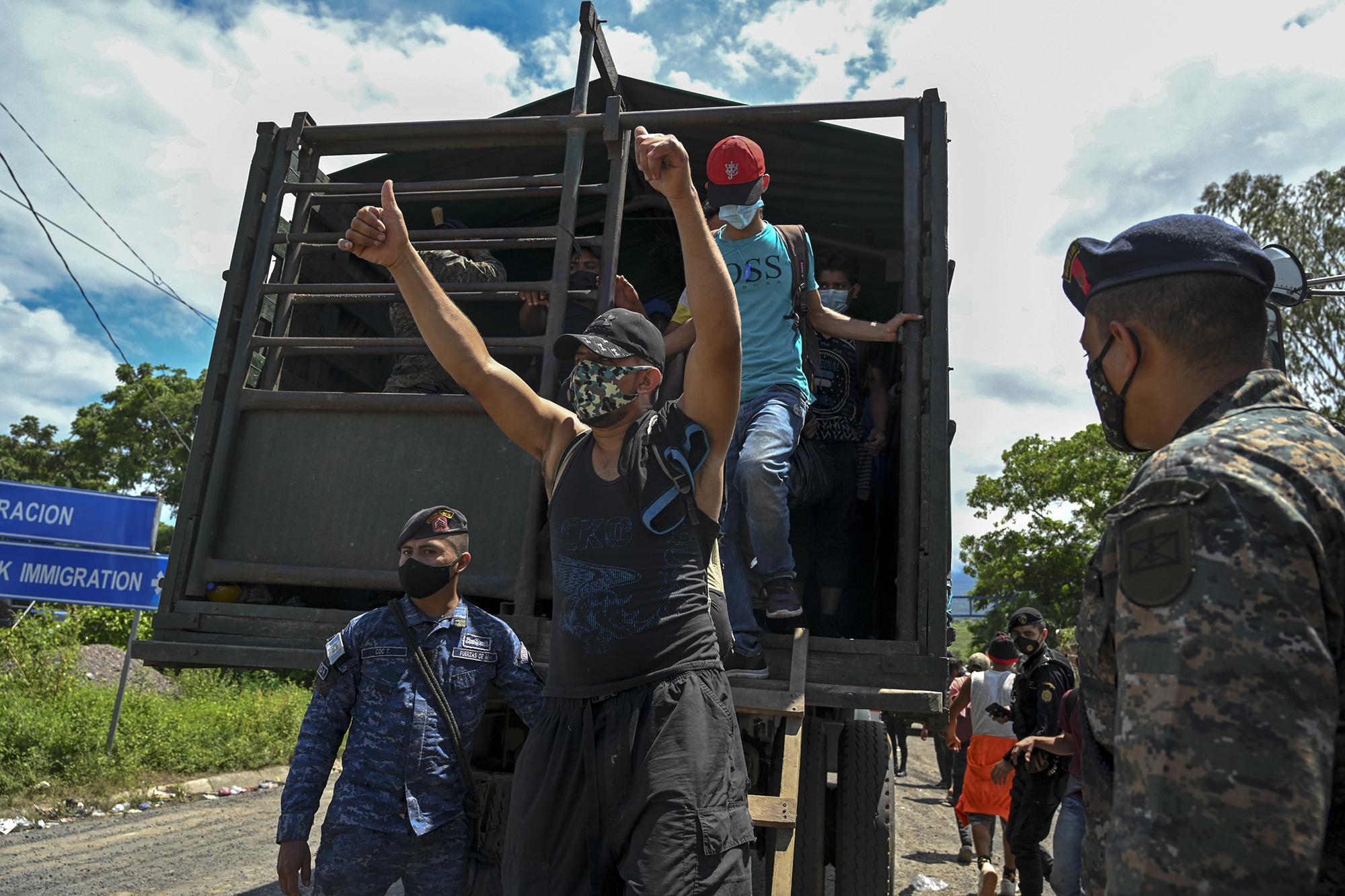 Honduran migrants who were heading in a caravan to the US, get off a Guatemalan army truck after voluntarily agreeing to return to Honduras, in Entre Rios, Guatemala, on October 3, 2020. - Over 2.000 Hondurans requested local authorities to return to their country, according to police data sent to journalists. Guatemalan President Alejandro Giammattei on Thursday had ordered the detention of thousands of Hondurans who entered the country as part of a US-bound migrant caravan. (Photo by Johan ORDONEZ / AFP)