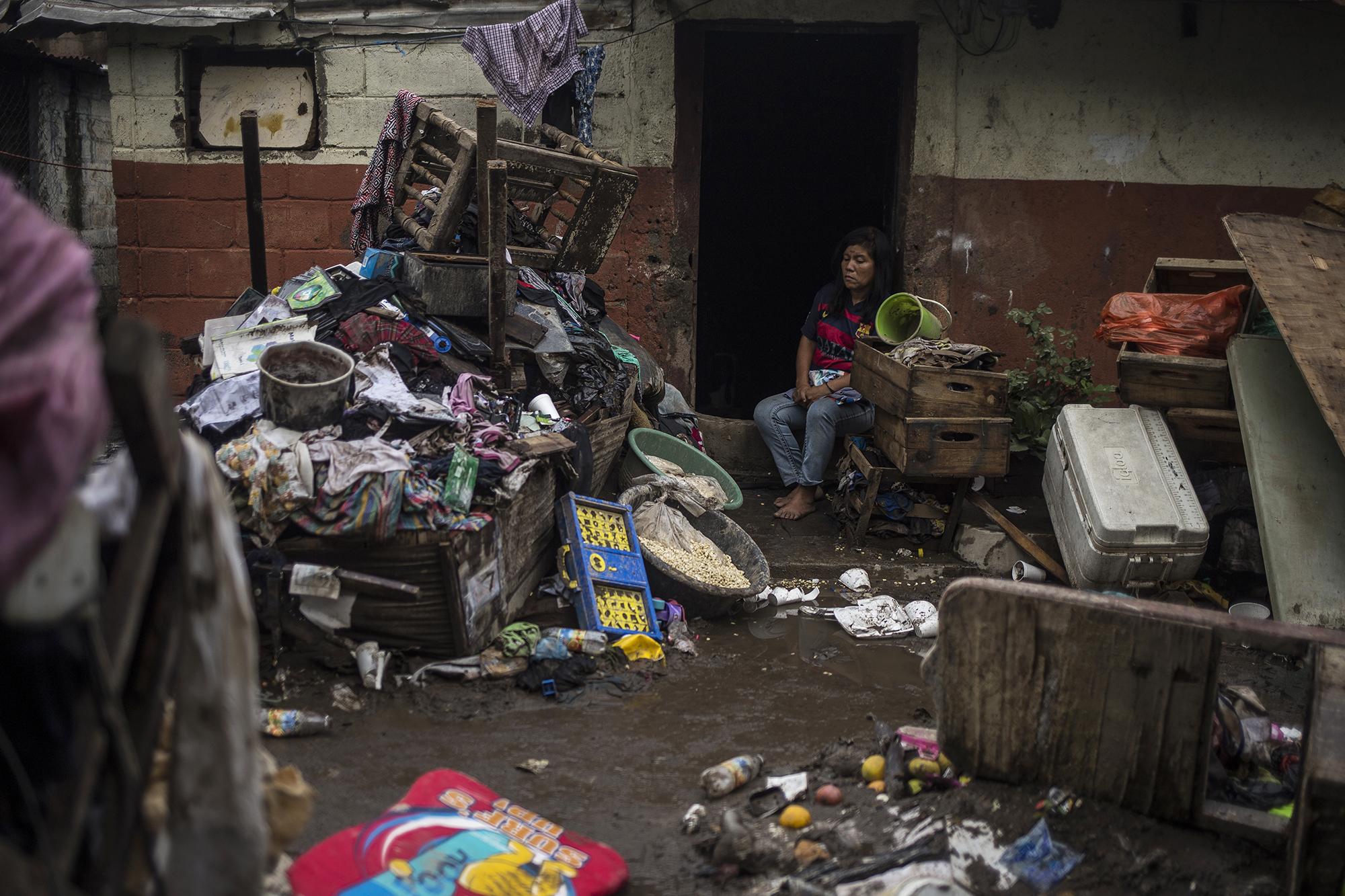 Comunidad El Granjero II, San Salvador. María Turcios, 38 años, y sus cinco hijos nadaron para salvar sus vidas el domingo 31 de mayo. El agua cubrió el techo de la vivienda y rompió las bisagras de las puertas. Sus pertenencias quedaron en la calle y todos sus alimentos se perdieron. María vendía pan francés en el mercado La Tiendona de San Salvador. La cuarentena obligatoria por la covid-19 le había impedido ganar dinero desde el 20 de marzo. A una desgracia sanitaria se sumó otra habitual: el colapso de los sistemas de drenaje de la ciudad durante el invierno. A finales de mayo, la tormenta tropical Amanda entró a El Salvador y decenas de comunidades empobrecidas y ubicadas en las riberas de ríos o en los bajos de la ciudad sufrieron los estragos. Foto de El Faro: Víctor Peña.
