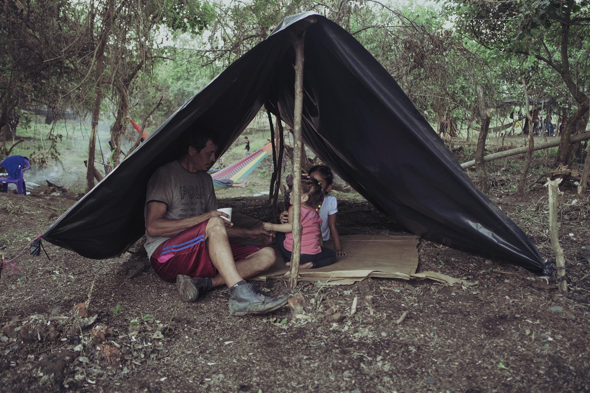 Sebastián Orellana descansaba con sus hijas bajo una carpa construida con palos y plástico en el terreno que ocupaban desde hacía un mes. Sebastián se dedica a la venta de productos de primera necesidad y durante la cuarentena no pudo salir a vender. A la precariedad laboral se sumaron los estragos del invierno, que inundó la comunidad en la que vivían, a la orilla del río Grande en San Miguel. Sebastián es de los líderes comunitarios y ayudó al resto en la construcción de las carpas. 