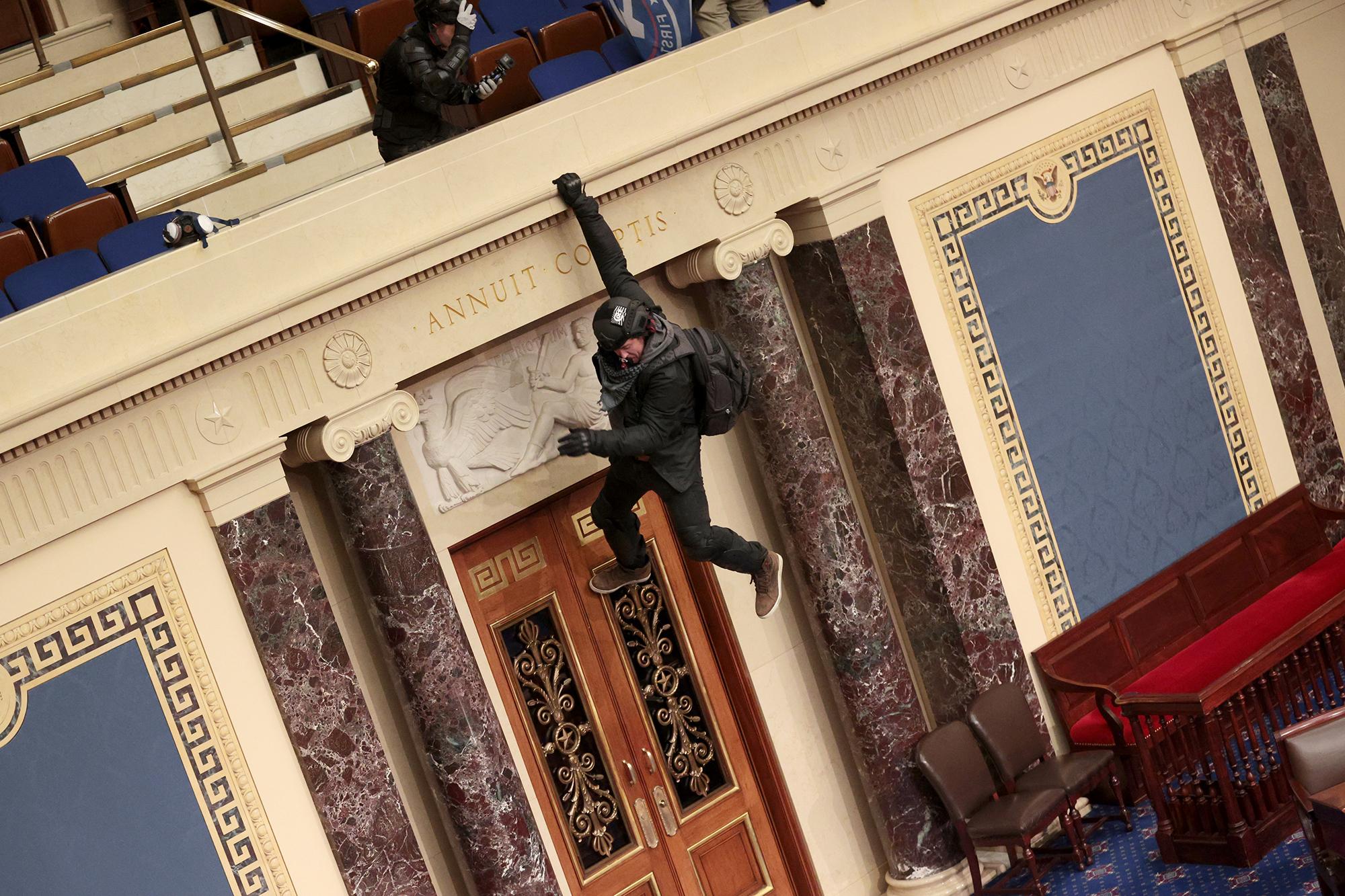 Se ve a un manifestante colgando del balcón en la Cámara del Senado el 6 de enero de 2021 en Washington, DC. El Congreso celebró una sesión conjunta hoy para ratificar la victoria del Colegio Electoral 306-232 del presidente electo Joe Biden sobre el presidente Donald Trump. Los manifestantes pro-Trump han ingresado al edificio del Capitolio de Estados Unidos después de manifestaciones masivas en la capital de la nación. Foto de El Faro: Win McNamee / Getty Images / AFP.