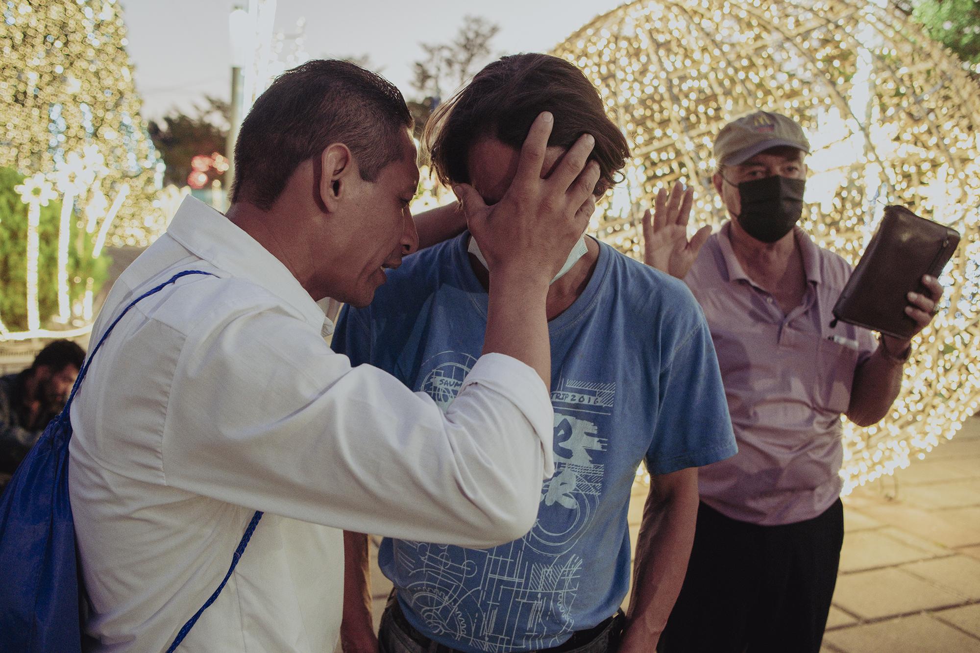 Marvin Valle ora por un hombre en la Plaza Libertad. El miembro de la Iglesia de la Calle no usaba mascarilla, sin temor a la COVID-19 acercaba su rostro al del otro hombre y le ponía las manos sobre la cara.