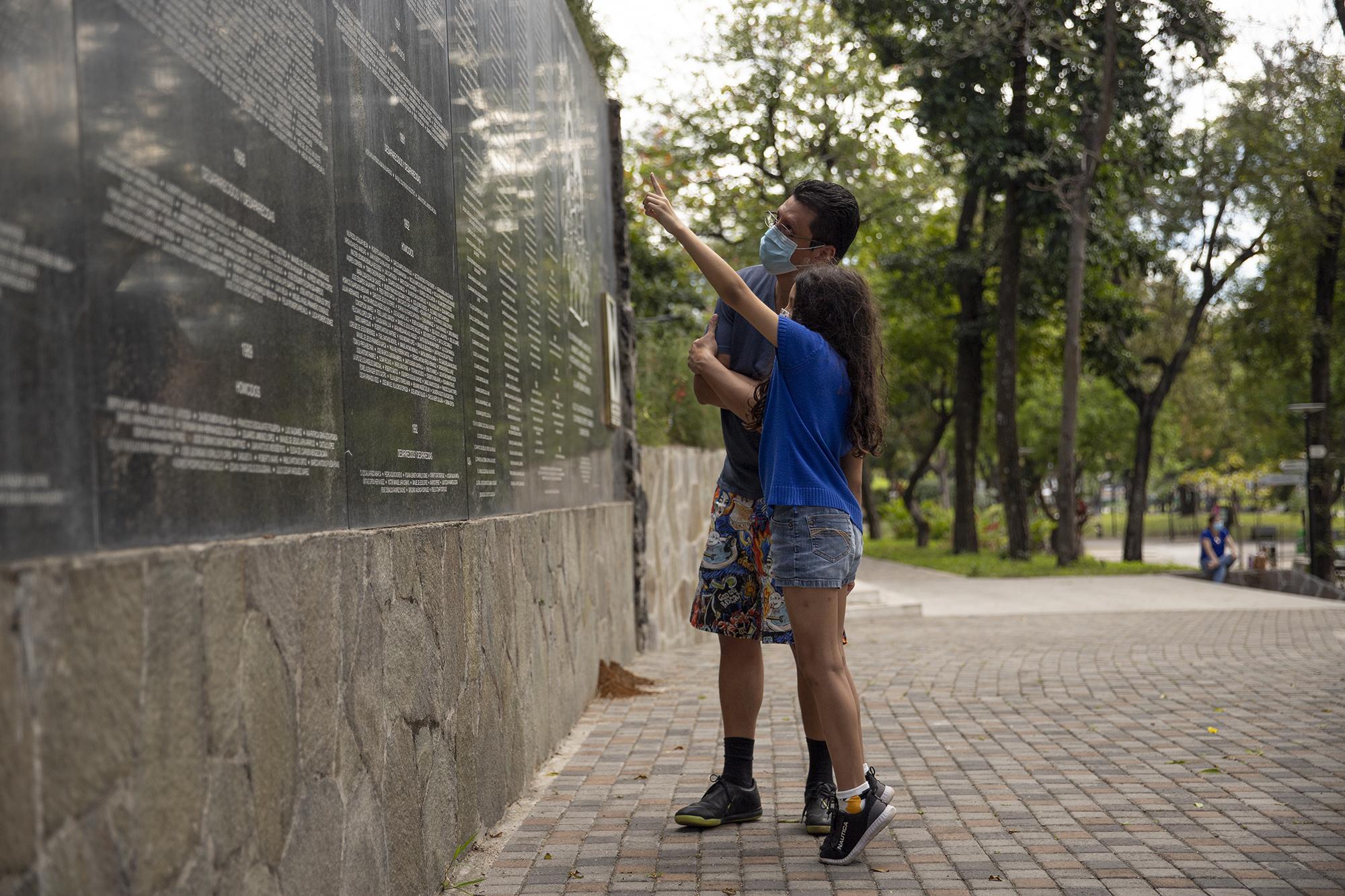 Eduardo Escobar y su hija Fabiola leen los nombres de las víctimas del conflicto armado de El Salvador en el monumento a la Memoria y la Verdad durante la conmemoración del 29 aniversario de la firma de los acuerdos de paz. Foto de El Faro: Carlos Barrera