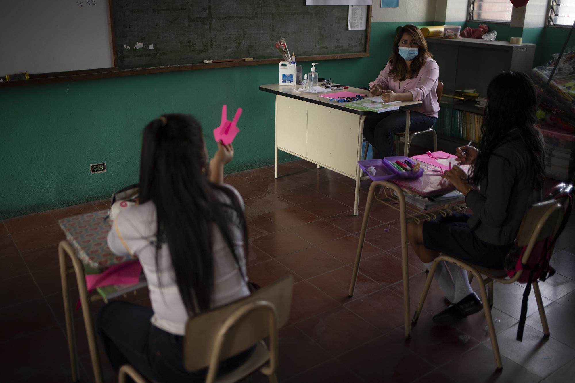 Cony López es maestra de aula acelerada del Centro Escolar República de Brasil, en su aula recibe alumnos que por diversas razones cortan su ciclo de estudios y se retrasan. Este año, según comenta, muchos de sus alumnos ya no van a llegar, unos por las dificultades económicas y otros por la violencia que se vive en las comunidades. El día del retorno solo asistieron dos alumnas a la clase de la maestra Cony.
