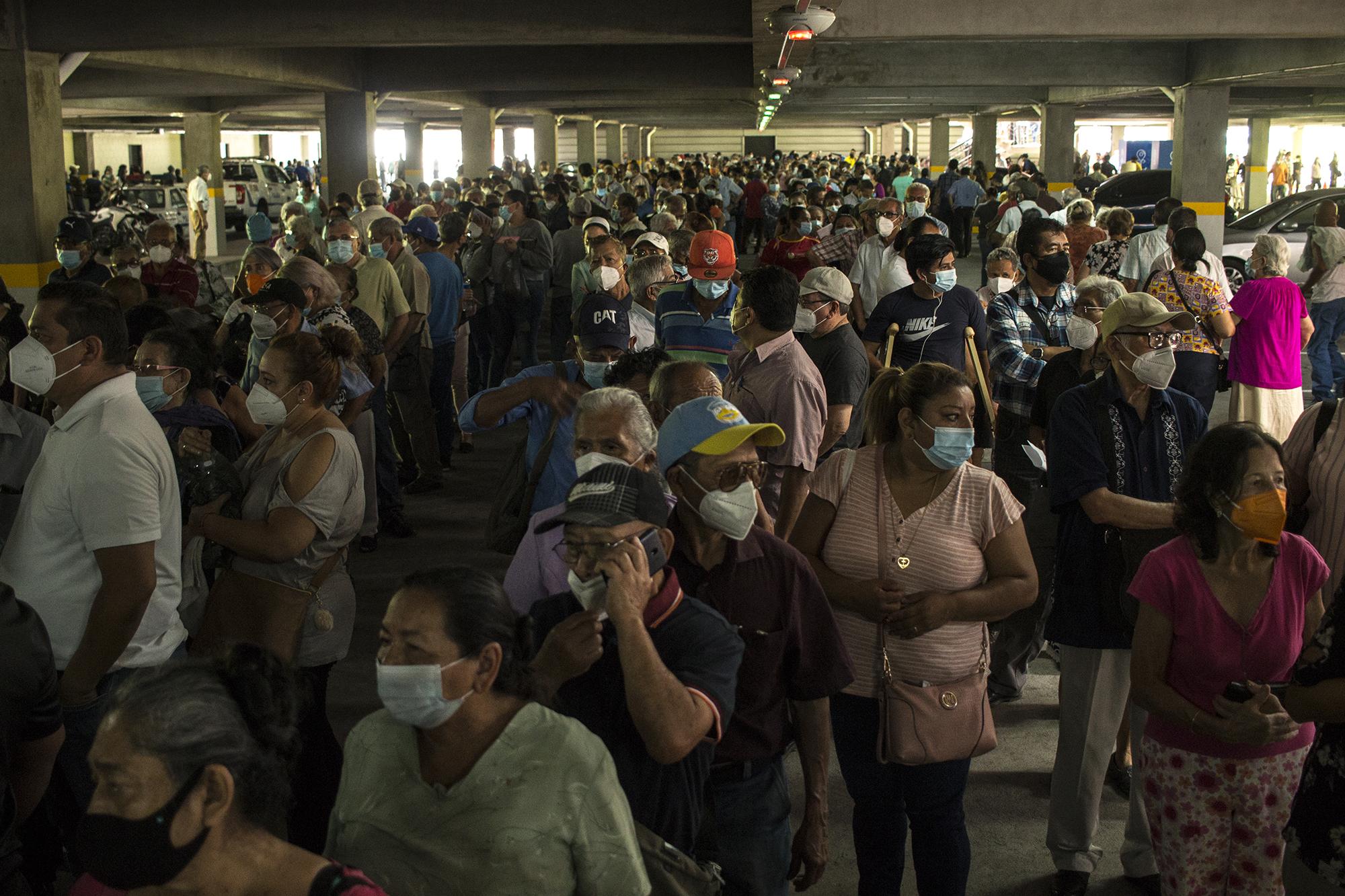 Cientos de personas se aglomeraron en el parqueo del centro comercial Metrocentro, de San Salvador. Muchos habían realizado su cita para recibir la primera dosis de la vacuna contra la covid-19. El Gobierno estableció este lugar como punto de reunión para el traslado de los beneficiarios, que en este caso, un procentaje mayor era mayor de 60 años. Foto de El Faro: Víctor Peña. 