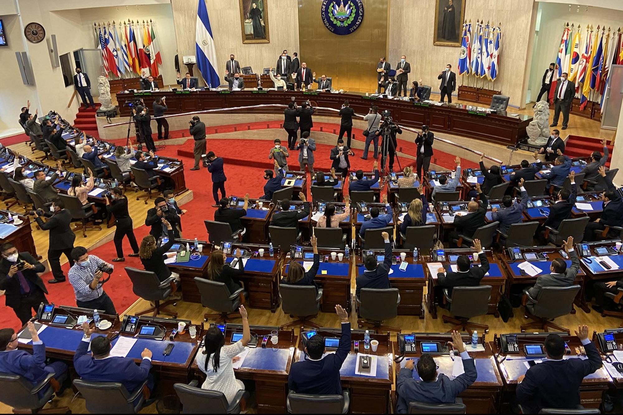 Los miembros de la bancada de Nuevas Ideas alzan la mano para aprobar la ley que convierte al bitcoin en moneda de uso en El Salvador, minutos después de la medianoche, en la madrugada del 9 de junio. Foto de El Faro: Nelson Rauda. 