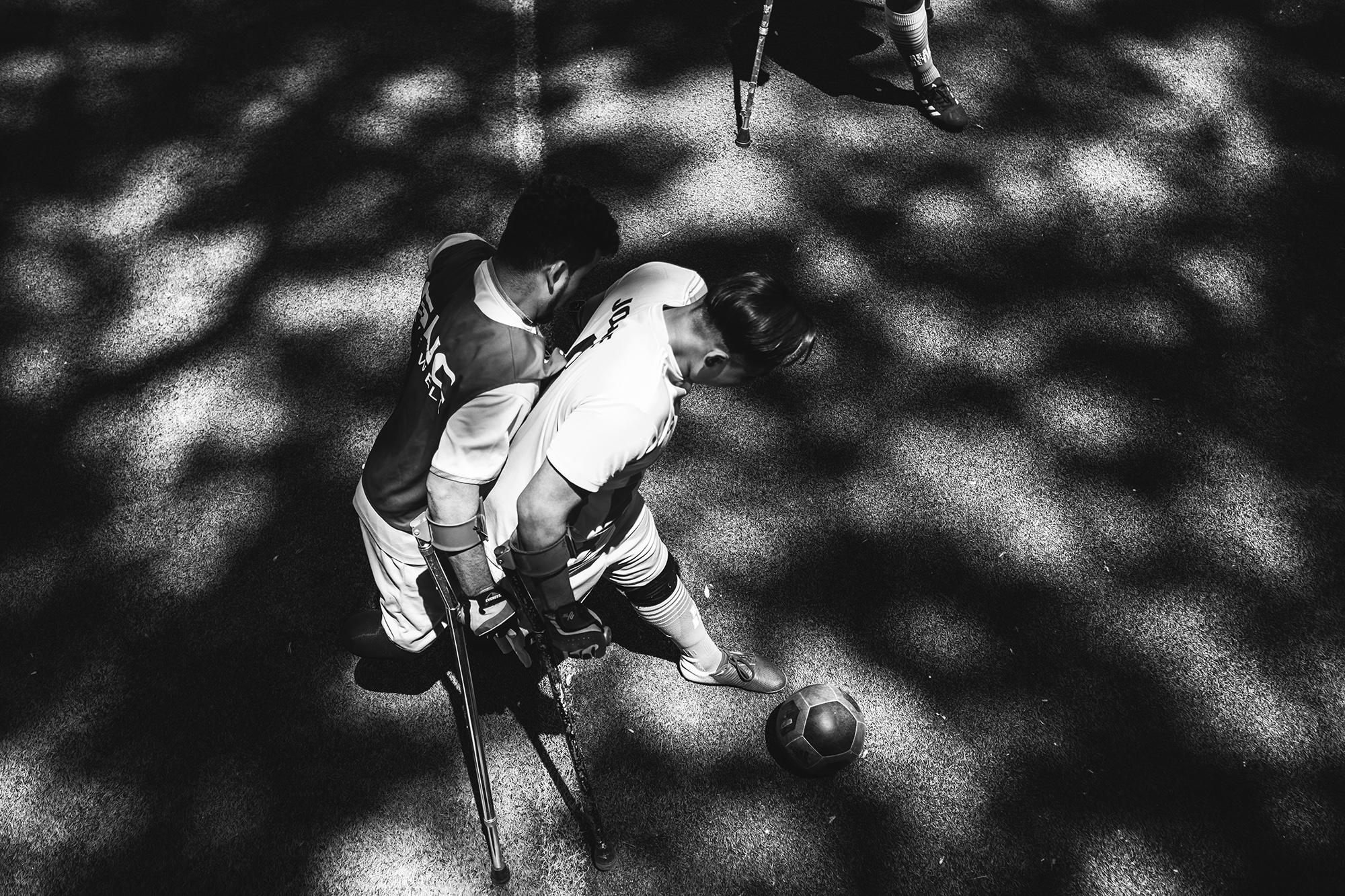 Alexánder Mejía, de 24 años, y Josué Pérez, de 19, en plena disputa del balón durante un entrenamiento en una cancha del municipio de Ciudad Delgado, San Salvador. Ambos futbolistas ya practicaban este deporte antes de ser amputados. Cuando perdieron sus miembros, según dicen, su vida se reinició. Alexánder, oriundo de Cojutepeque, perdió su pierna derecha después de ser arrollado por un vehículo mientras se conducía en su motocicleta. Josué, debió ser amputado de su pierna derecha debido a un osteosarcoma que surgió después de un golpe en su rodilla.