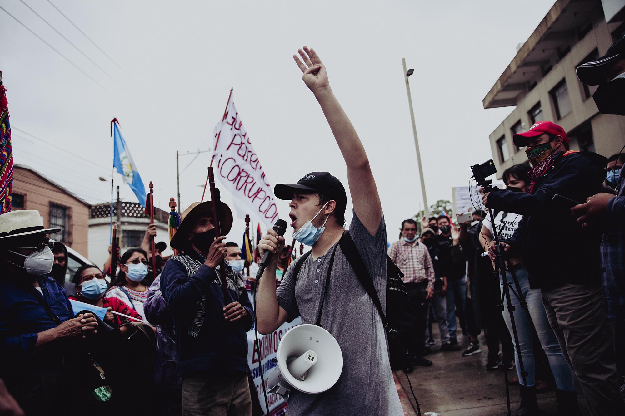 El líder estudiantil Jorge Búcaro se dirige a manifestantes reunidos frente al Ministerio Público en Ciudad de Guatemala el 29 de julio de 2021. Los estudiantes se unieron a la convocatoria de las autoridades indígenas al paro nacional para exigir la renuncia de Consuelo Porras y que Juan Francisco Sandoval recupere su puesto al frente de la FECI. Foto de El Faro: Carlos Barrera