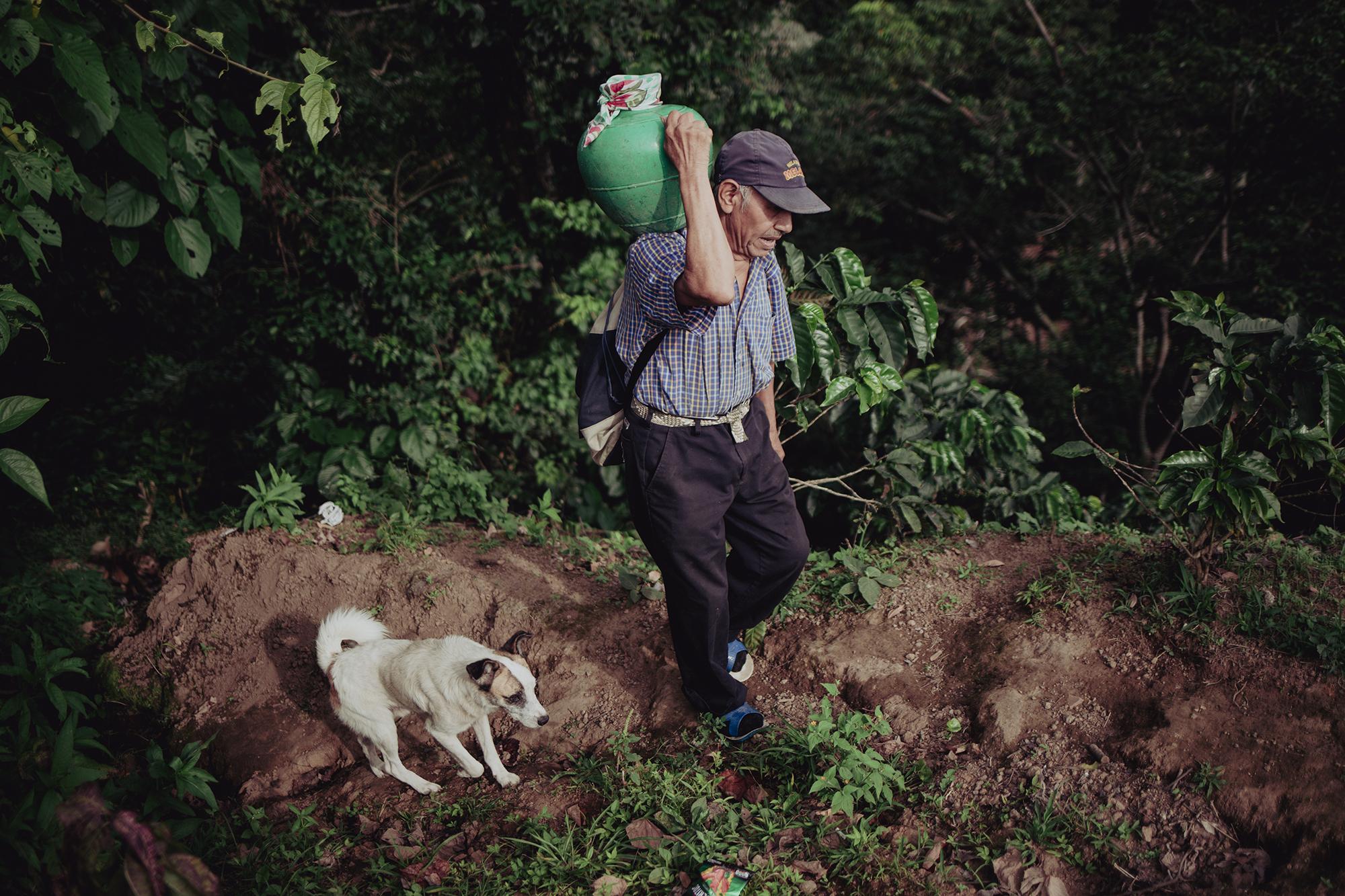 Pedro Mendoza, de 64 años, camina todos los días sobre un terreno escabroso para recolectar agua para él y su familia en el cantón San Lorenzo, Berlín. Allí no existen conexiones de agua potable en las casas de las comunidades y los habitantes se ven obligados a caminar durante al menos 30 minutos para abastecerse. Foto de El Faro: Carlos Barrera