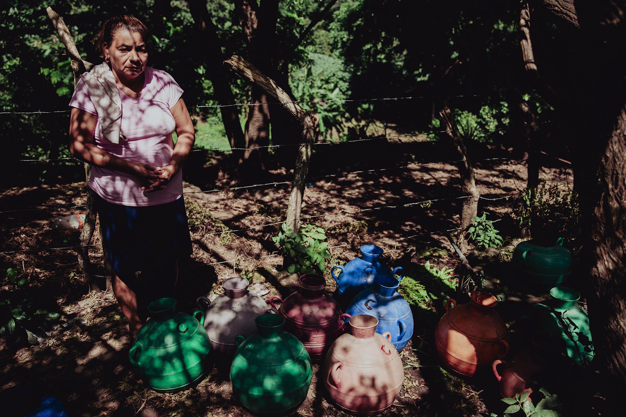 Consuelo del Carmen Cruz espera a un lado de una calle polvorienta a que se llenen sus cántaros de un chorro ubicado en el cantón Loma Alta, del municipio de Berlín, Usulután. Foto de El Faro: Carlos Barrera