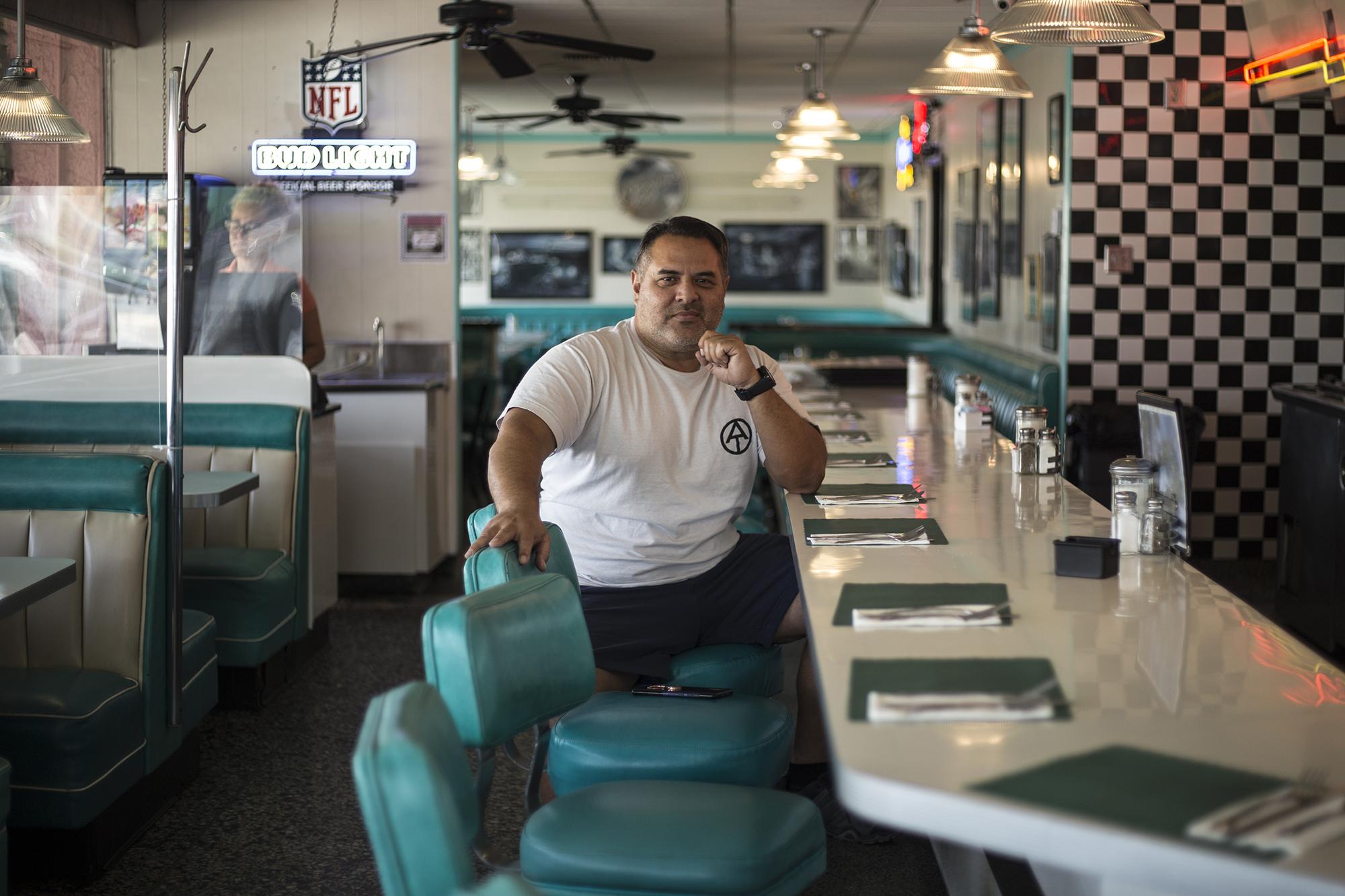 Giovanni Pérez posa en las instalaciones de Ozzie´s Diner, un bar de carretera en Bells Garden, California. Con su trabajo como camionero sostuvo a sus cuatro hijos, entre ellos el delantero de la selección Joshua Pérez. Giovanni es hermano del entrenador Hugo Pérez, y creció en el centro de Los Ángeles, inmerso en el territorio del Barrio 18, y llegó a jugar en el Club Deportivo FAS. Se retiró del fútbol en 1994.