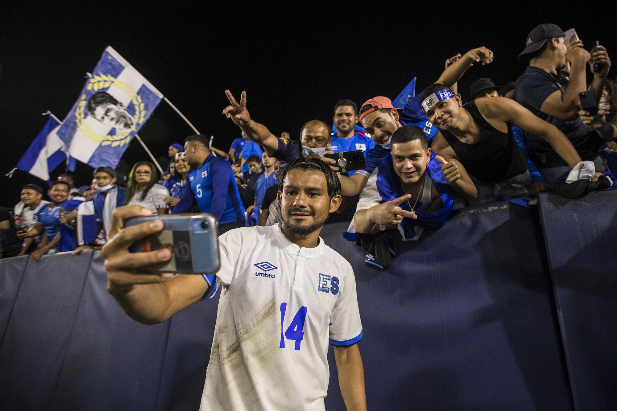 Wilma Torres, volante de El Salvador, interactúa con los aficionados en Los Ángeles, tras el amistoso  contra Costa Rica el 21 de agosto de 2021. Un jugador que se pone la camisa de la Selecta es un héroe nacional para los salvadoreños en Estados Unidos, sin importar los resultados. Al fondo se eleva una bandera con el rostro de Mauricio Cienfuegos, retirado desde hace 20 años, que por casi una década convirtió al Galaxy de la MLS en un referente para la diáspora salvadoreña. 