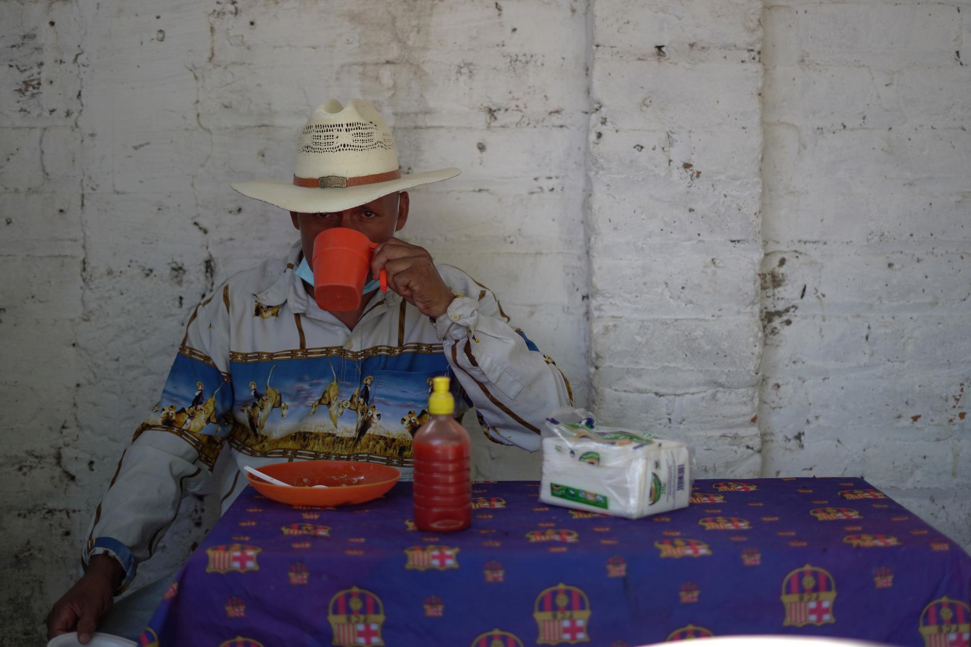 Un comerciante de ganado desayuna en el tiangue del municipio de San Rafael Cedros, en el departamento de Cuscatlán, el sábado 10 de julio de 2021. El tiangue es el centro de negocios para ganaderos y agricultores. Es una feria itinerante en distintos municipios y una práctica histórica en El Salvador desde finales del siglo XIX. La entrada en vigencia del bitcóin como moneda legal en El Salvador, contrasta mucho ante la idea de negocio de un tiangue, donde sus comerciantes negocian con dinero en efectivo e incluso con el intercambio de bienes. Foto de El Faro: Víctor Peña.    