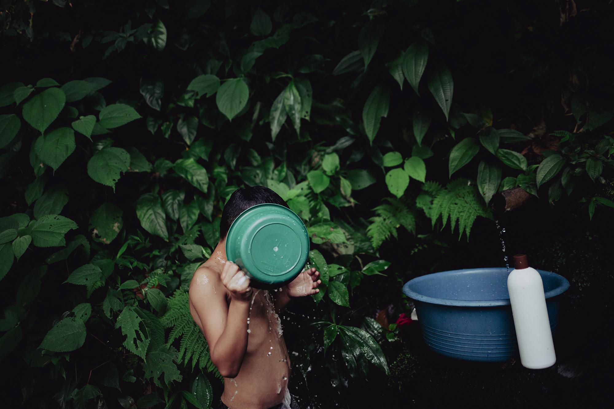 Justin Velázquez, de 8 años, vive en el cantón San Lorenzo, de Berlín, Usulután. El 22 de julio del 2021, como todos los días, el niño acompañó a su madre hasta el nacimiento de agua para poder bañarse y llevar agua para su familia. Foto de El Faro: Carlos Barrera