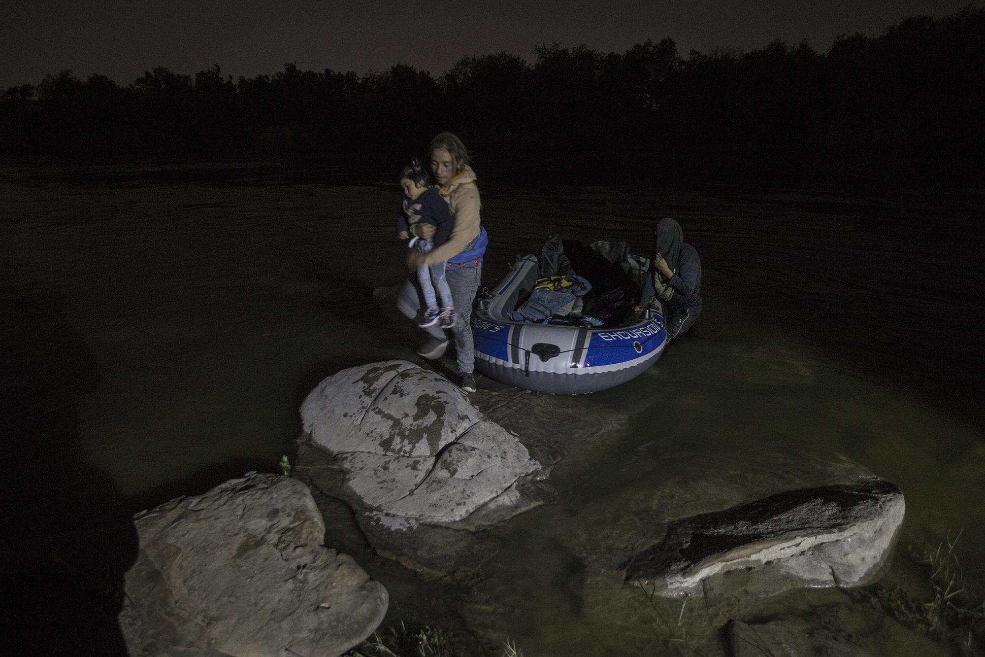 Heydi Aguilar, de 20 años, baja de una balsa, la noche del sábado 27 de marzo, en el río Bravo, en Roma, Texas. Camina sobre las piedras y toca Estados Unidos. Ella es la última en bajar de esta balsa. Carga a su hijo de dos años, con quien migraba desde el 28 de febrero, desde el departamento de San Marcos, en Guatemala. Foto de El Faro: Víctor Peña.