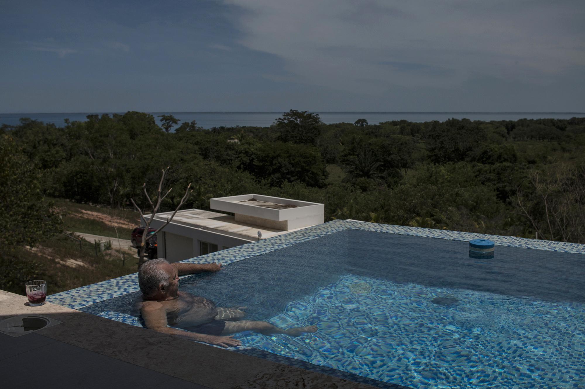 Óscar Nájera observa el mar Caribe desde su piscina en el complejo privado NJOI, al que se llega por calles polvosas. Está ubicado en medio de las comunidades garífunas que rodean el municipio de Trujillo, en Colón, Honduras. Durante el juicio en Nueva York contra Tony Hernández, Nájera fue señalado como un nexo entre los hermanos Rivera Maradiaga y el presidente Juan Orlando Hernández  para coordinar el retiro de retenes militares y policiales para el paso de la droga. En las elecciones hondureñas de noviembre, Nájera perdió la inmunidad que la política hondureña le permitió por más de 30 años.  Foto de El Faro: Víctor Peña. 