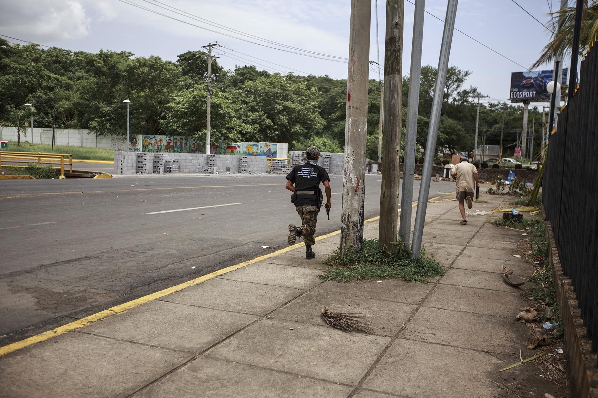 Two armed students, one carrying a 9 millimeter pistol and the other an improvised mortar, run to the university