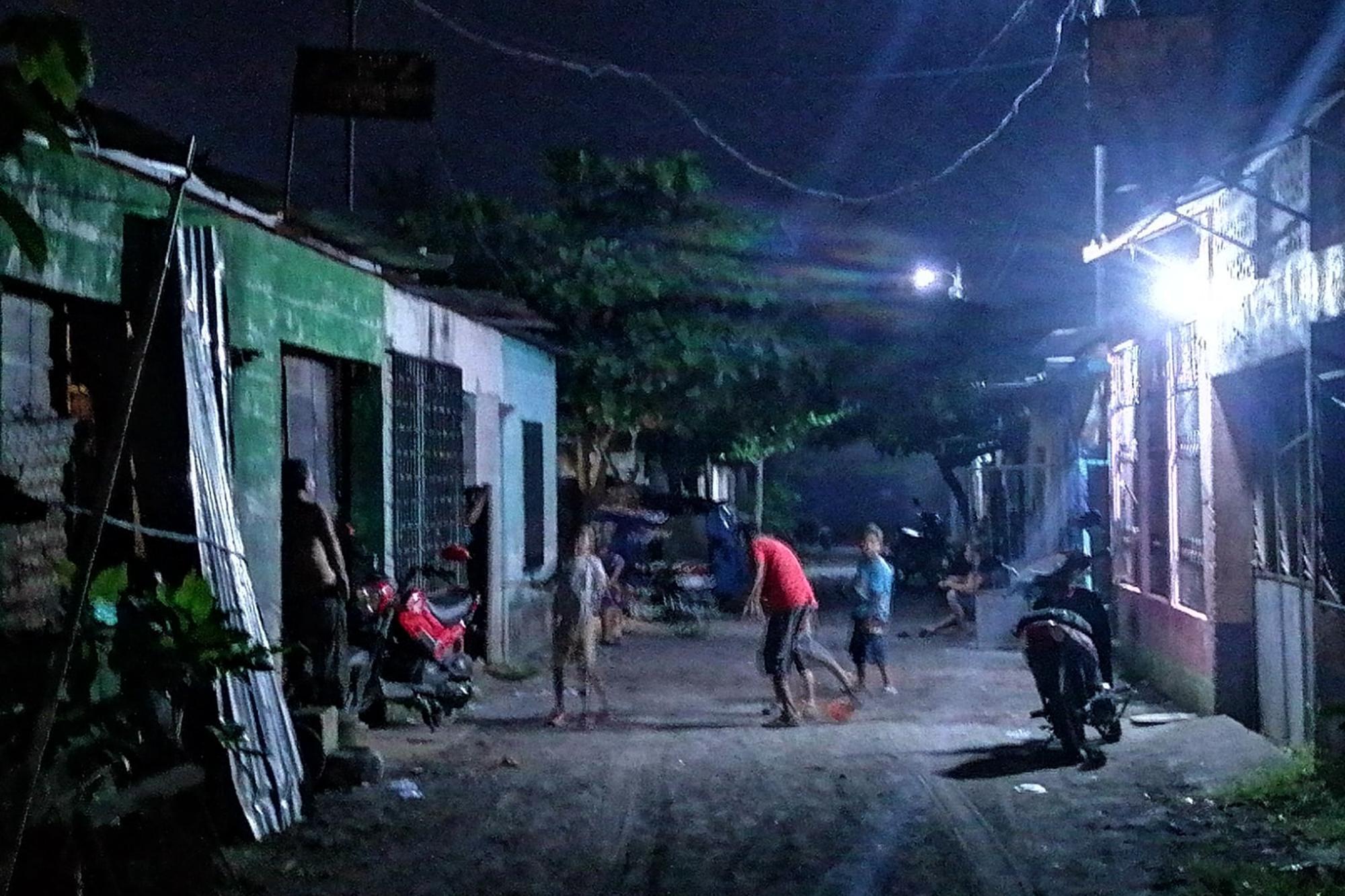 Y a pesar de todo, aún hay cotidianidad en Shalom. Una familia juega en uno de los callejones de tierra de la colonia tras el ocaso. Foto: Gilberto Escobar. 