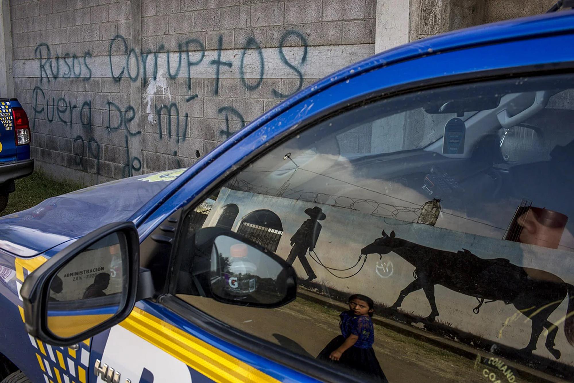 Un letrero denuncia la presencia del proyecto extractivista con capital ruso frente al centro polideportivo de El Estor, transformado, durante el estado de sitio, en el centro de operaciones de Policía y Ejército.Foto cortesía Simone Dalmasso/ Plaza Pública.