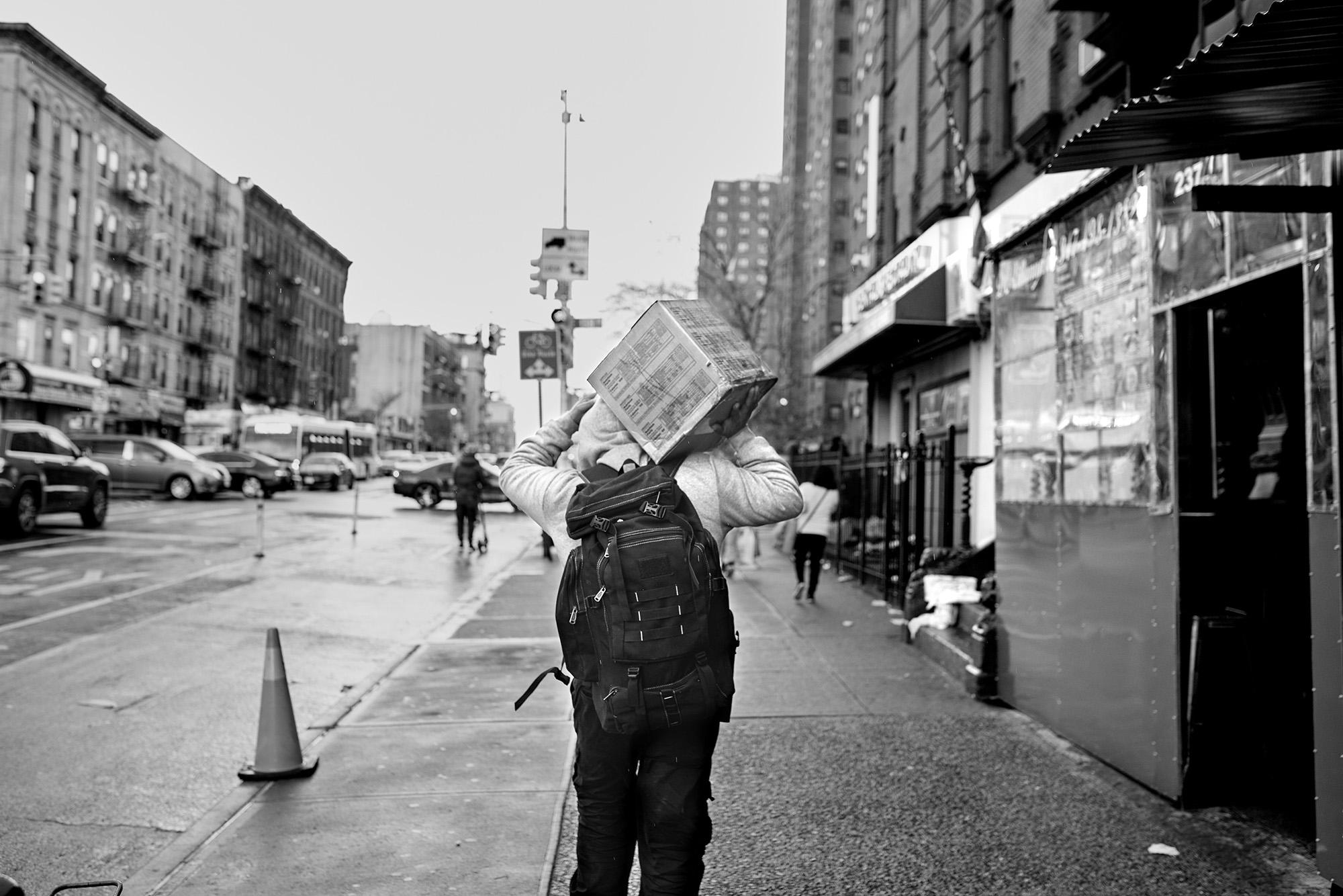 Un hombre carga una caja de comida la primera avenida de Nueva York, en la zona sur del Bronx. La caja le fue entregada por la red de solidaridad del padre Fabián Arias. El Gobierno estadounidense quiso paliar el golpe económico de la pandemia con una serie de “cheques de estímulo”. Los migrantes indocumentados, uno de los colectivos más afectados por la crisis de salud,  nunca recibió ese cheque. Foto de El Faro: Edu Ponces/ Ruido Photo.