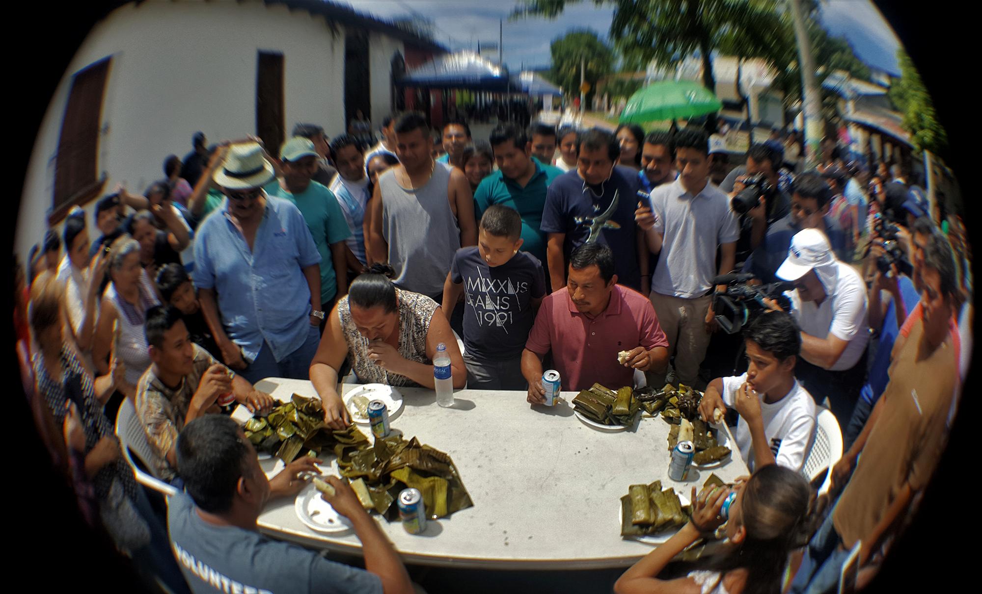 Uno de los platos fuertes en el programa del IV Festival del Tamal de San Pedro Perulapán fue el comelón de tamales: comer diez tamales en menos de cinco minutos. El concurso lo ganó Estela Ayala (sentada frente a la cámara, comiendo), y con ello se quedó con el premio de 30 dólares. Foto Roberto Valencia (El Faro).