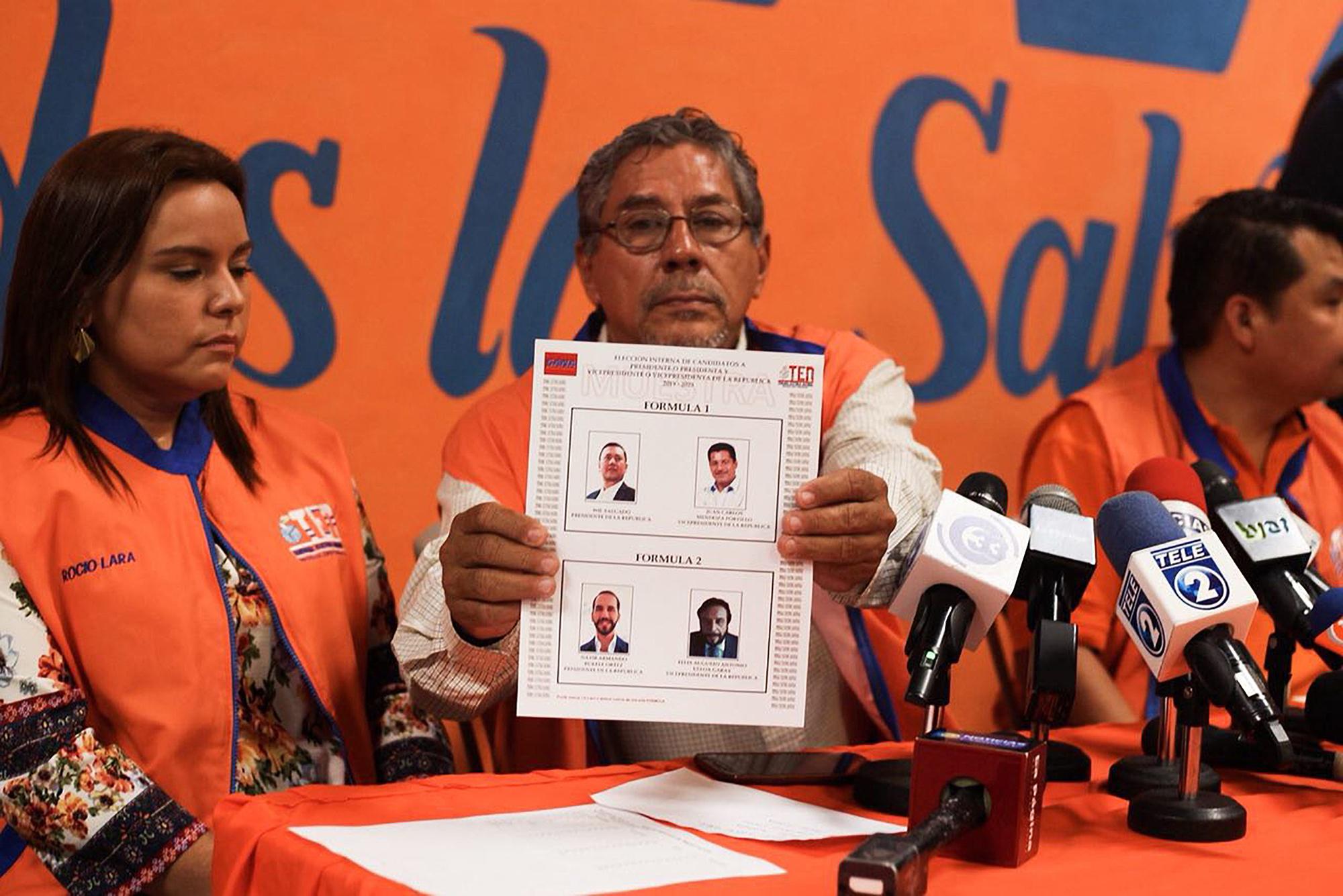 Miembros del comité electoral de Gana muestran la papeleta a usar en las internas, el domingo 29 de julio de 2018, para elegir candidato presidencial. Foto de El Faro: Fred Ramos.