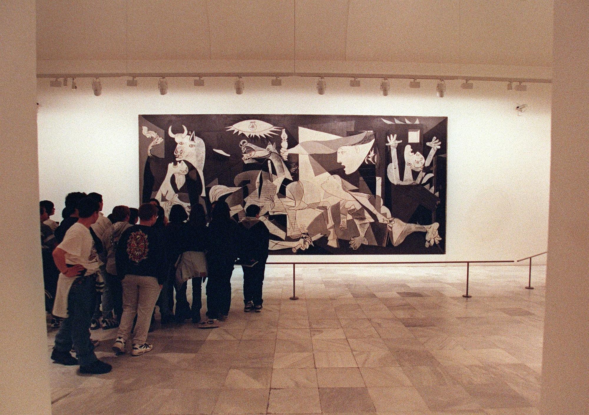 Un grupo de estudiantes desfila el 23 de abril de 1997 frente al ‘Guernica’, considerada por muchos críticos la obra cumbre de Pablo Picasso. Desde entonces el imponente cuadro es el principal reclamo del Museo Reina Sofía, en Madrid. Foto Dominique Faget (AFP).
