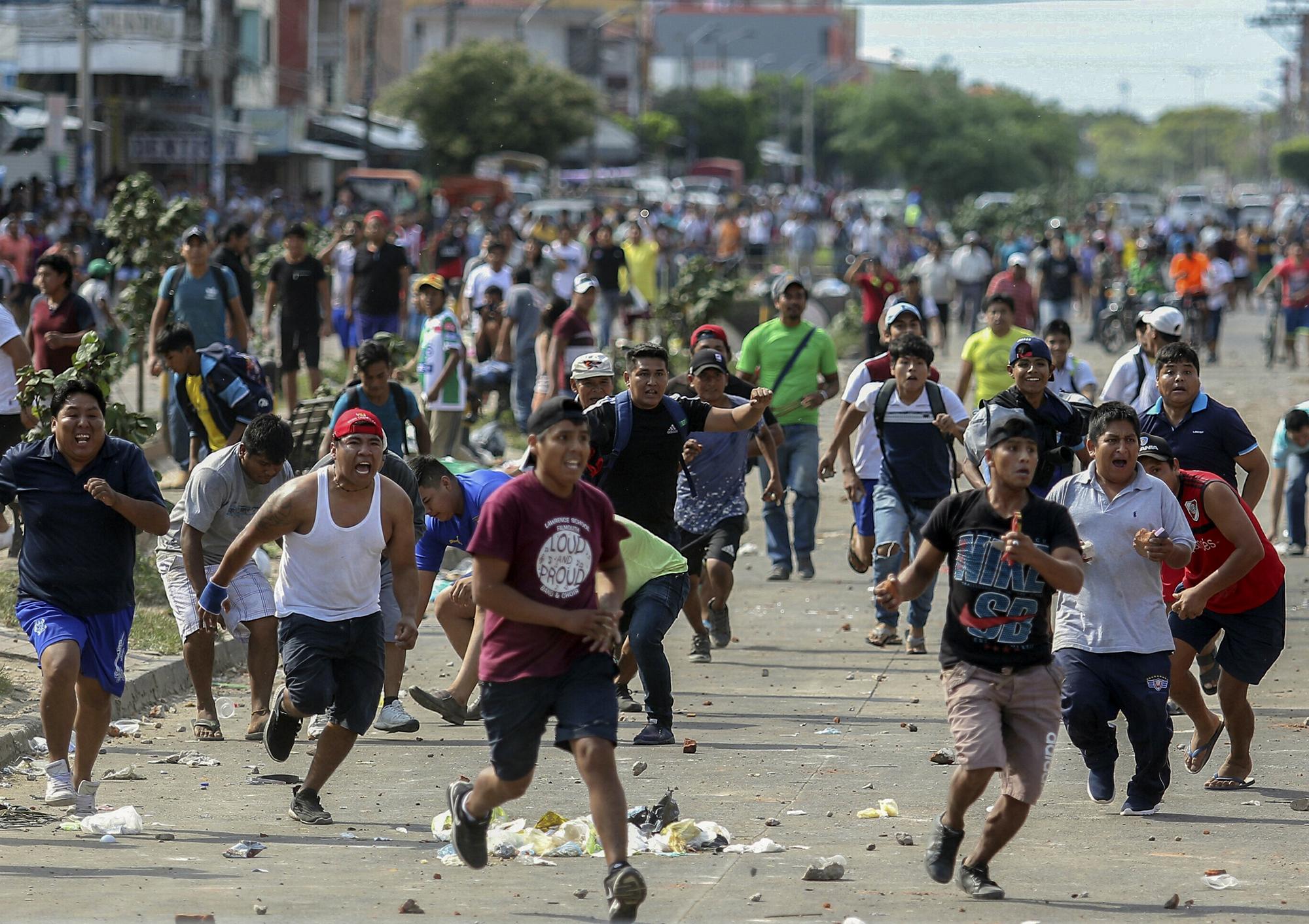 Los partidarios del candidato de la oposición boliviana Carlos Mesa y del presidente Evo Morales se enfrentan por los resultados elecorales en disputa, en Santa Cruz, Bolivia, el 23 de octubre de 2019.  La oposición de Bolivia lanzó una huelga general el miércoles en medio de protestas y disturbios por los resultados de las elecciones en las que Morales busca otro término. El presidente vinculó el paro con un golpe de la derecha. Foto por Daniel Walker / AFP.