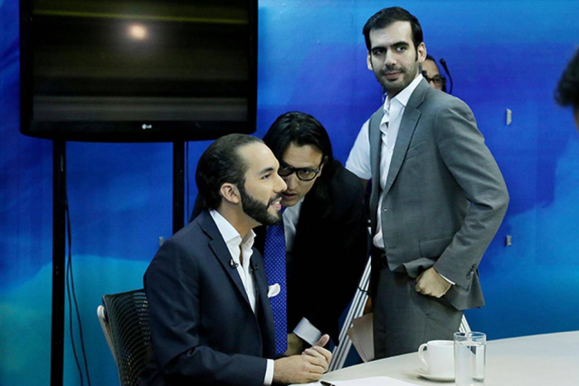 In a January 2015 television debate leading up to the municipal elections, then FMLN mayoral candidate, Nayib Bukele, listens to instructions from Ernesto Sanabria (now his Press Secretary), and his brother, Karim (gray jacket). Photo Fred Ramos