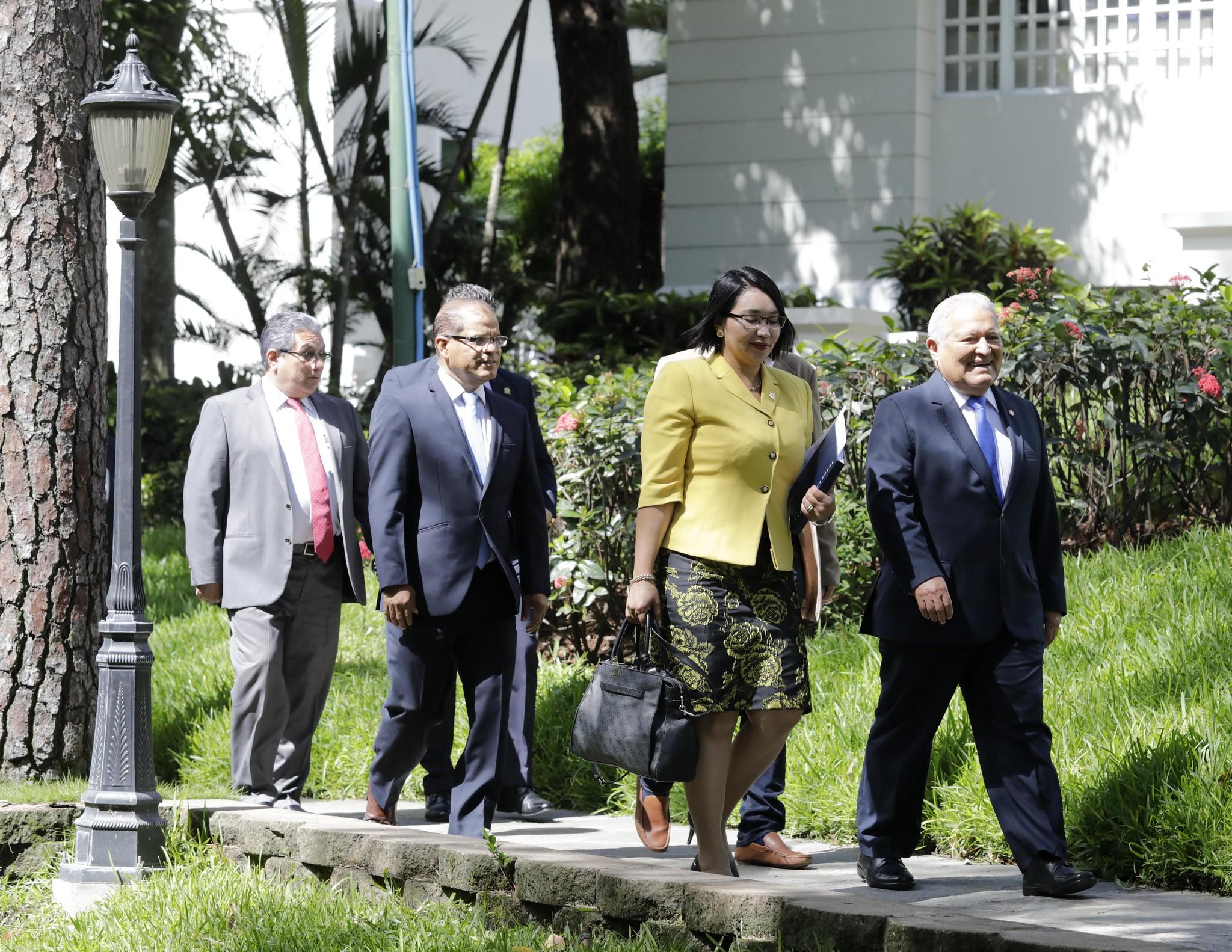 El presidente Sánchez Cerén (derecha) camina junto a la presidenta de la Corte de Cuentas, Carmen Elena Rivas Landaverde. El 27 de mayo de 2019, se llevó a cabo la entrega de 14 informes pactados en una guía de transición, en un proceso en el que no participó la administración del presidente entrante Nayib Bukele, y en el que no incluyó la fiscalización de los gastos reservados de Casa Presidencial.