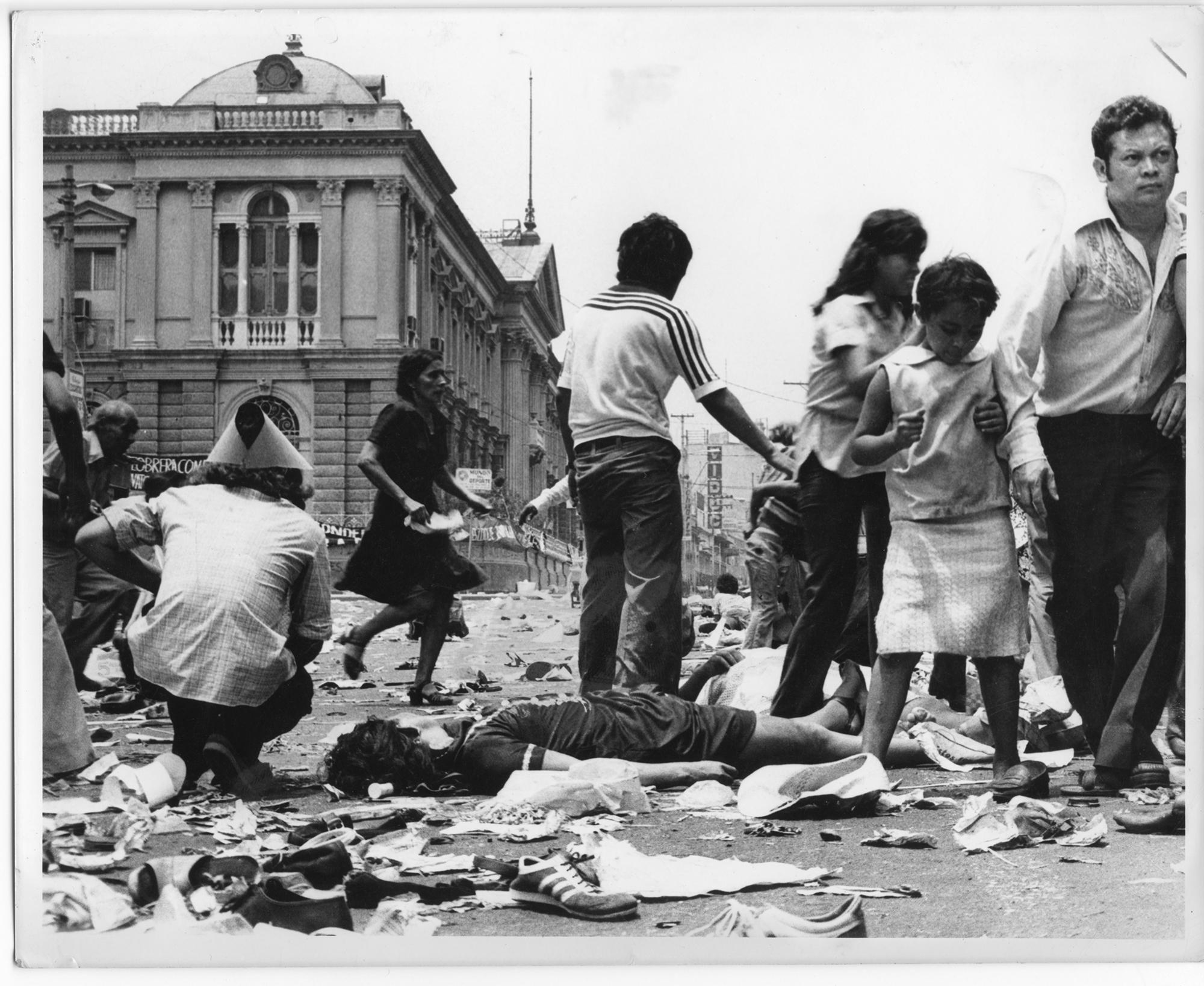 Una mujer yace en el suelo mientras la gente se dispersa tras escuchar los disparos en los funerales de monseñor Óscar Arnulfo Romero, en la Plaza Barrios, de San Salvador, el 30 de marzo de 1980. Foto: Cortesía del Museo de la Palabra y la Imagen.