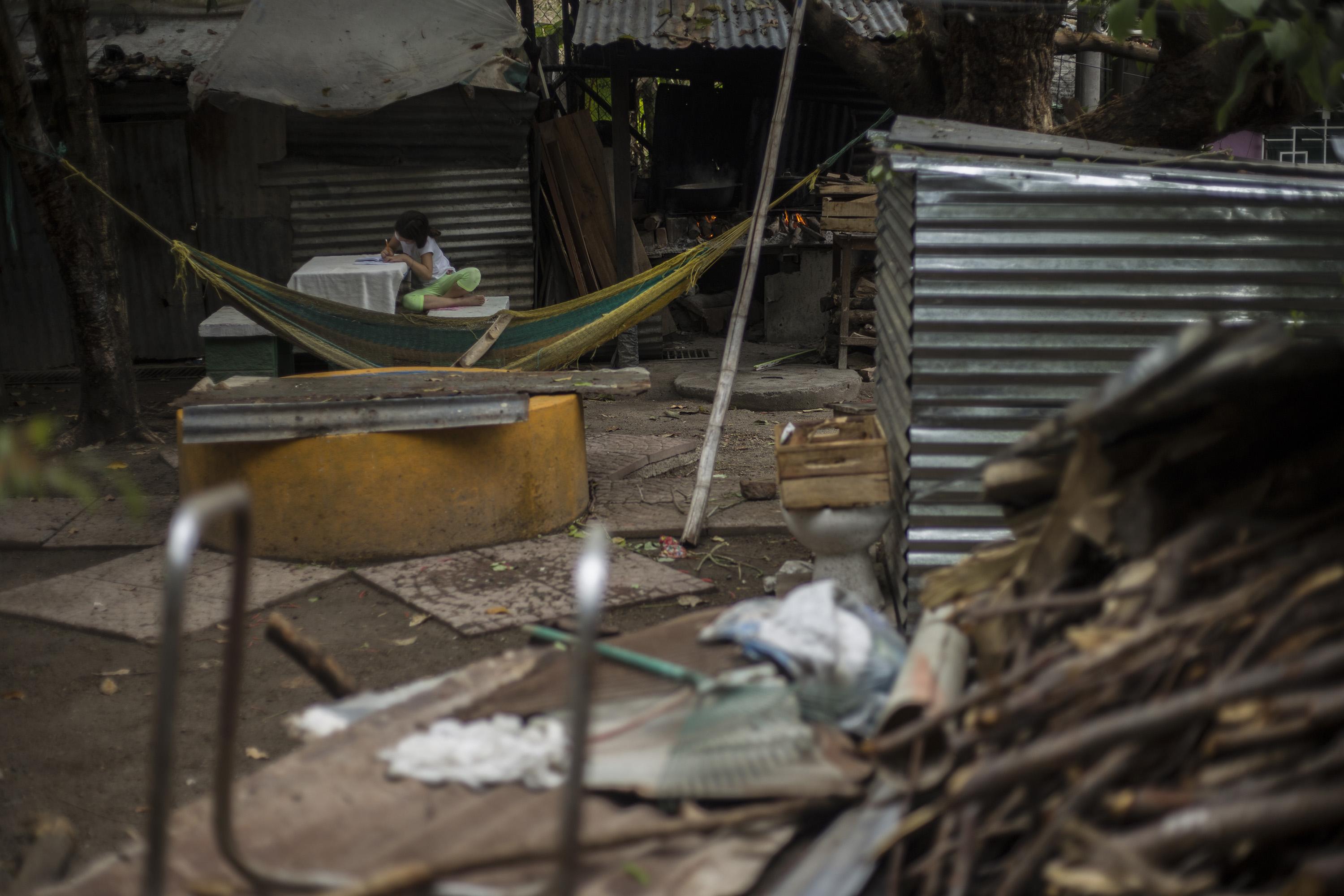 Emely, de siete años, hace sus tareas escolares en un traspatio, al final de la 22 de Abril, una de las comunidades más violentas, ubicada entre el límite de los municipios de San Salvador y Soyapango. El miércoles 30 de marzo, la Fuerza Armada y la Policía Nacional Civil realizaron un operativo dedicado a revisar casa por casa, como parte del Régimen de Excepción que la Asamblea Legislativa aprobó después del alza de homicidios. Ingresar a estas colonias bajo control criminal solo es posible en momentos como este, cuando hay un despliegue de fuerzas de seguridad. Foto de El Faro: Víctor Peña.