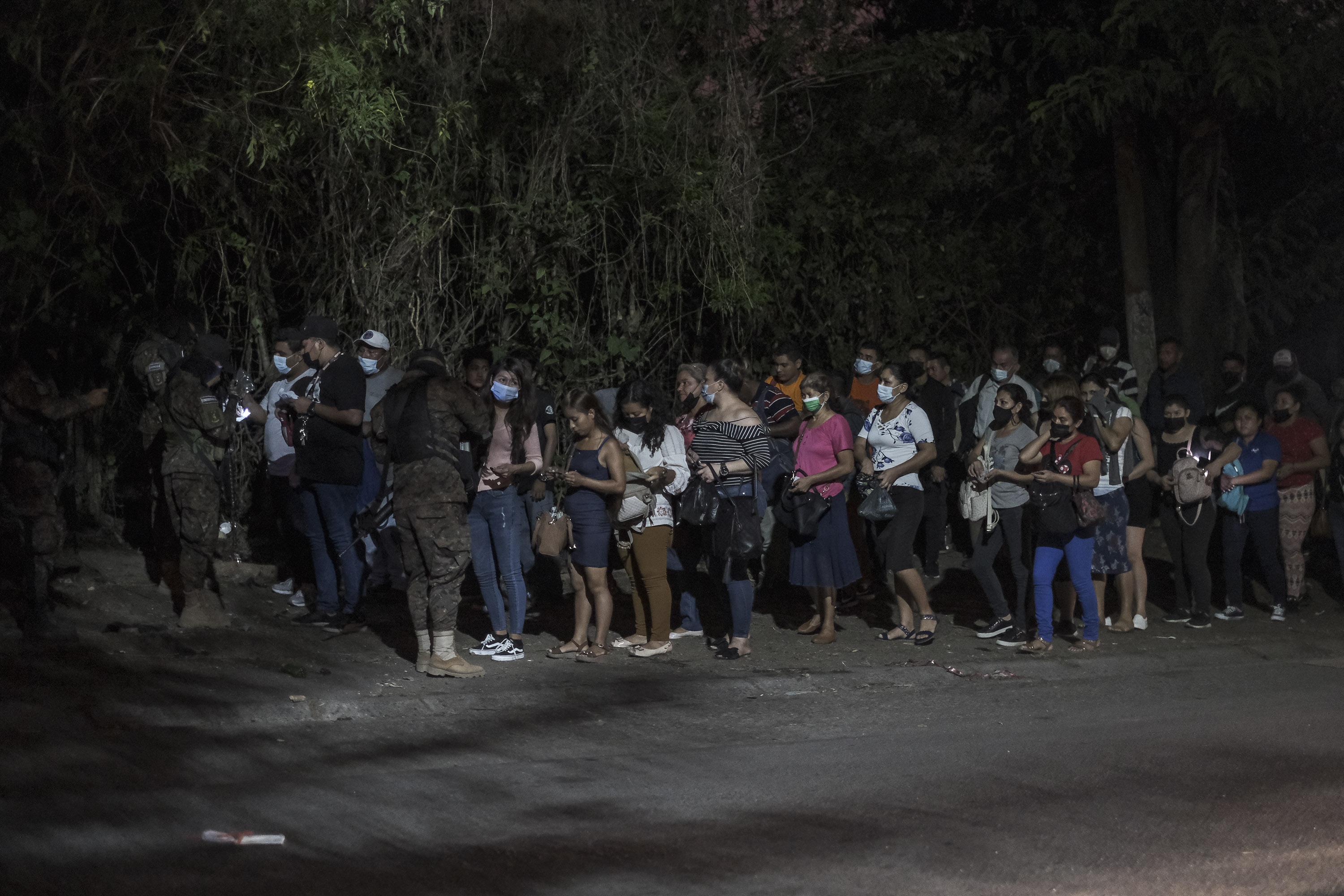 Durante las noches, las personas que regresan de sus trabajos al Distrito Italia, en Tonacatepe, tienen que hacer largas filas para poder ingresar a su zona de residencia. En la entrada al lugar, los militares revisan las pertenencias y piden los documentos personales para verificar que la dirección de su identificación indique que la persona es residente del lugar. Foto de El Faro: Carlos Barrera.