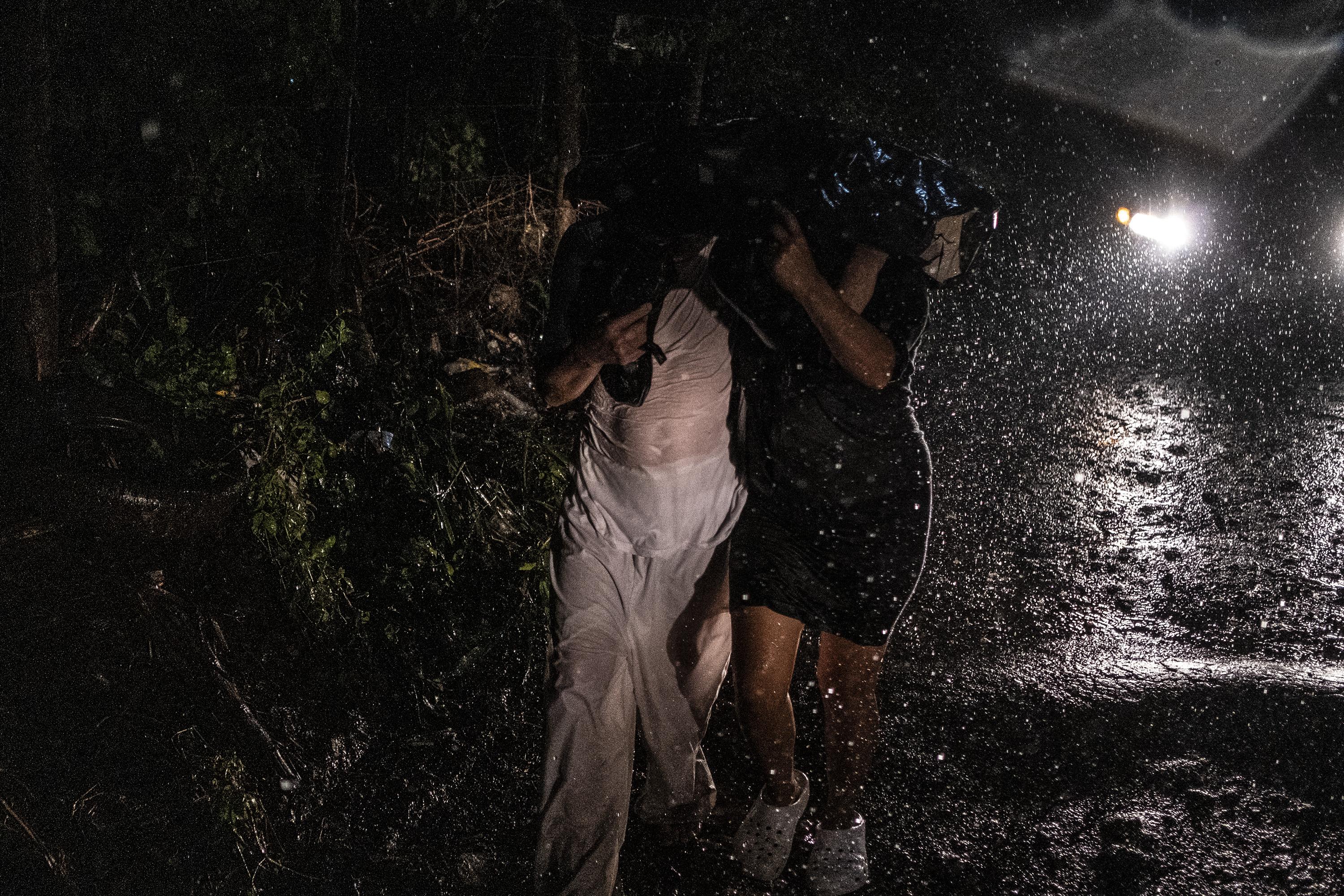 La noche del 27 de abril fueron liberados del penal de Izalco cuatro hombres que habían sido capturados en diferentes puntos de El Salvador durante el Régimen de Excepción. Uno de los liberados, aún con el uniforme blanco y de nombre Julio, caminó abrazado de su pareja y bajo la lluvia después de que la mujer, con cinco meses de embarazo, esperó durante dos días en el mismo lugar a que él fuera liberado. Foto de El Faro: Carlos Barrera